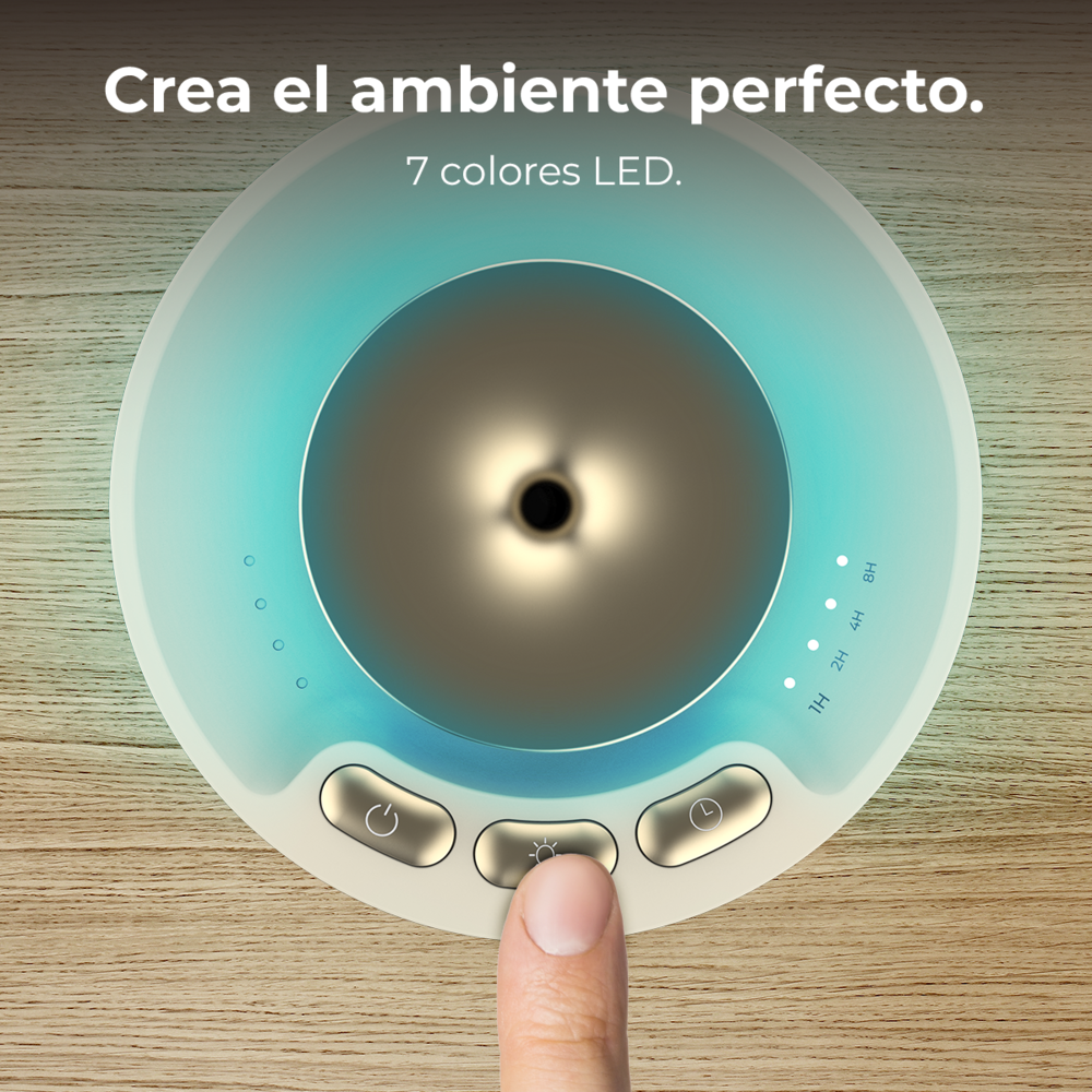 Un dedo pulsa el botón de luz de un difusor redondo con iluminación turquesa sobre madera.