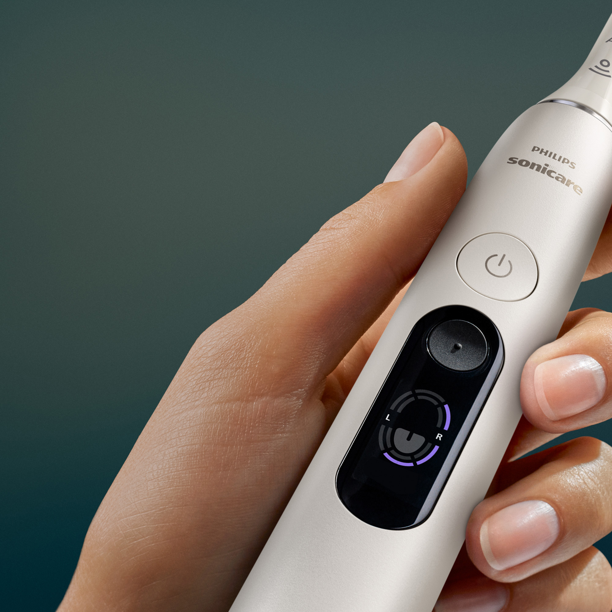 Dłoń trzyma białą elektryczną szczoteczkę do zębów Philips Sonicare z wyświetlaczem cyfrowym.