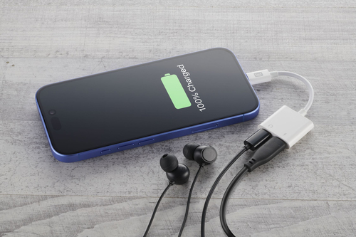 Un teléfono azul se carga en una superficie de madera clara, conectado a un adaptador blanco y auriculares.