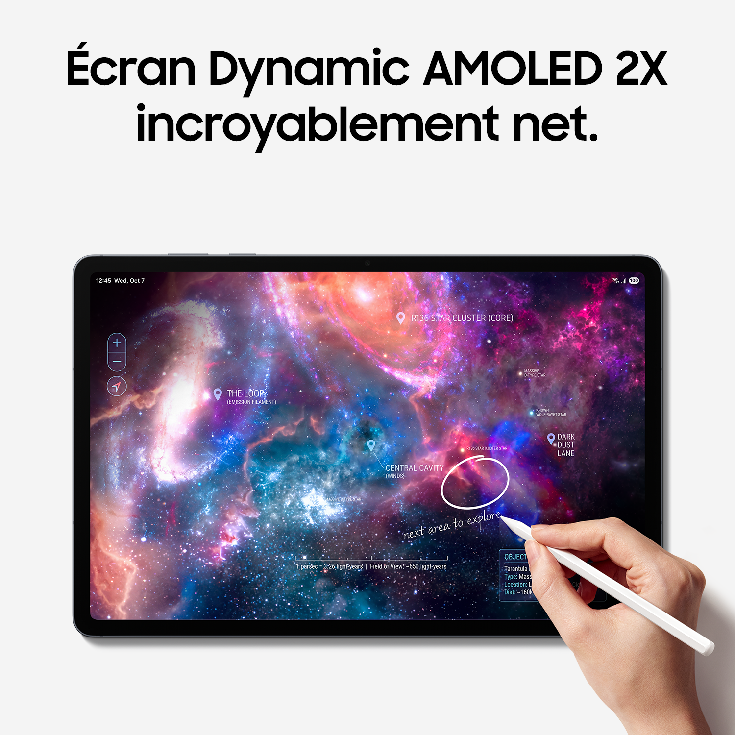 Une main utilise un stylet sur une tablette affichant une galaxie colorée.