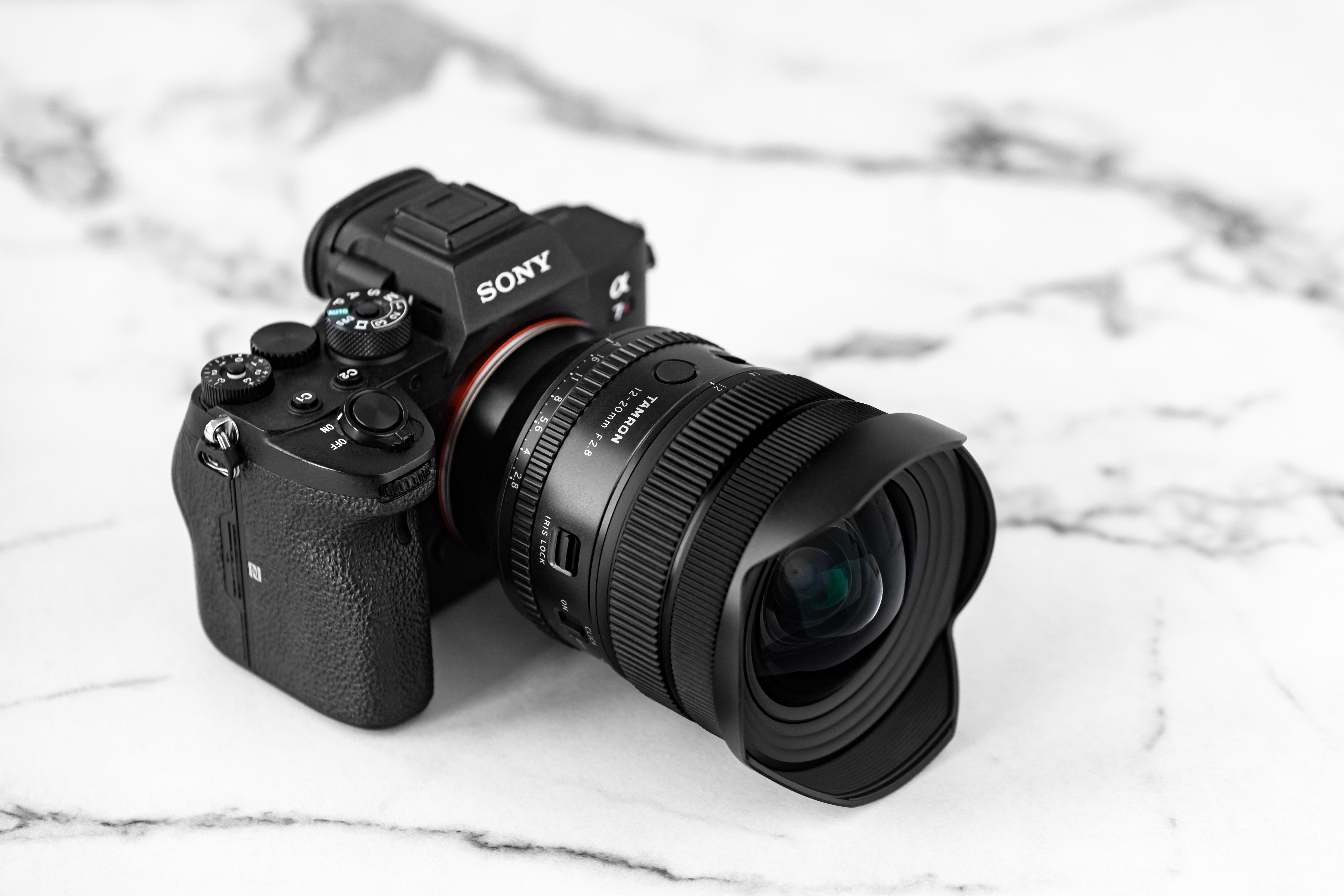 Eine schwarze Sony-Kamera mit Tamron-Objektiv liegt auf einer weiß marmorierten Oberfläche.