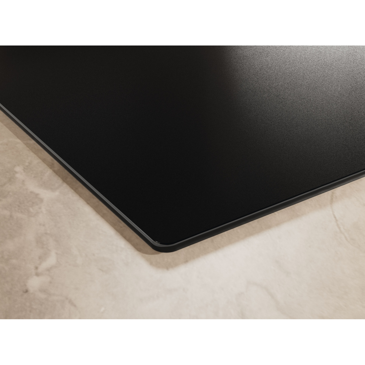Angolo di un piano cottura nero su marmo beige.