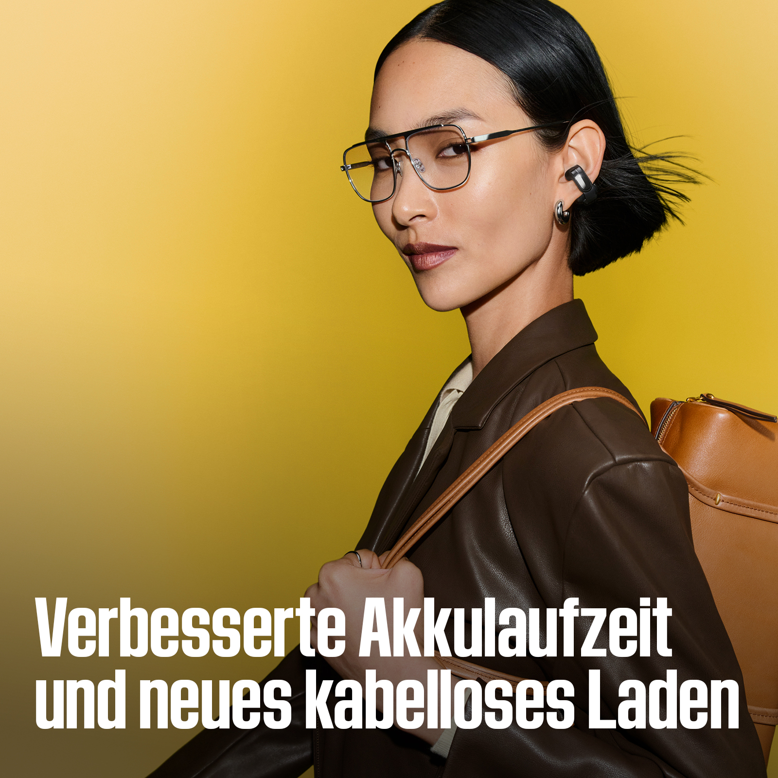 Eine Frau mit Brille, Ohrhörern und brauner Jacke vor gelbem Hintergrund. Text unten.