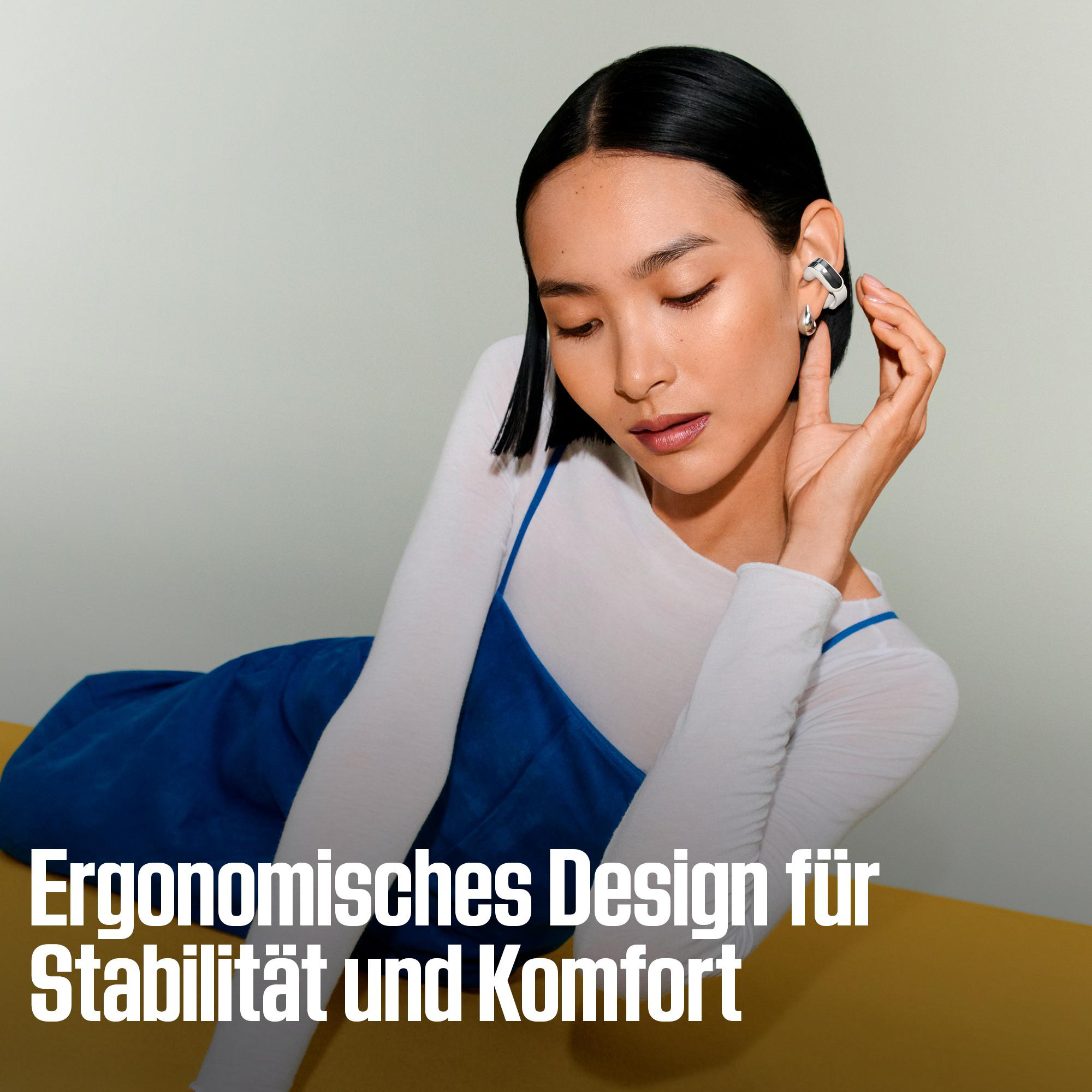 Eine Frau mit weißen Kopfhörern lehnt auf einer gelben Fläche.