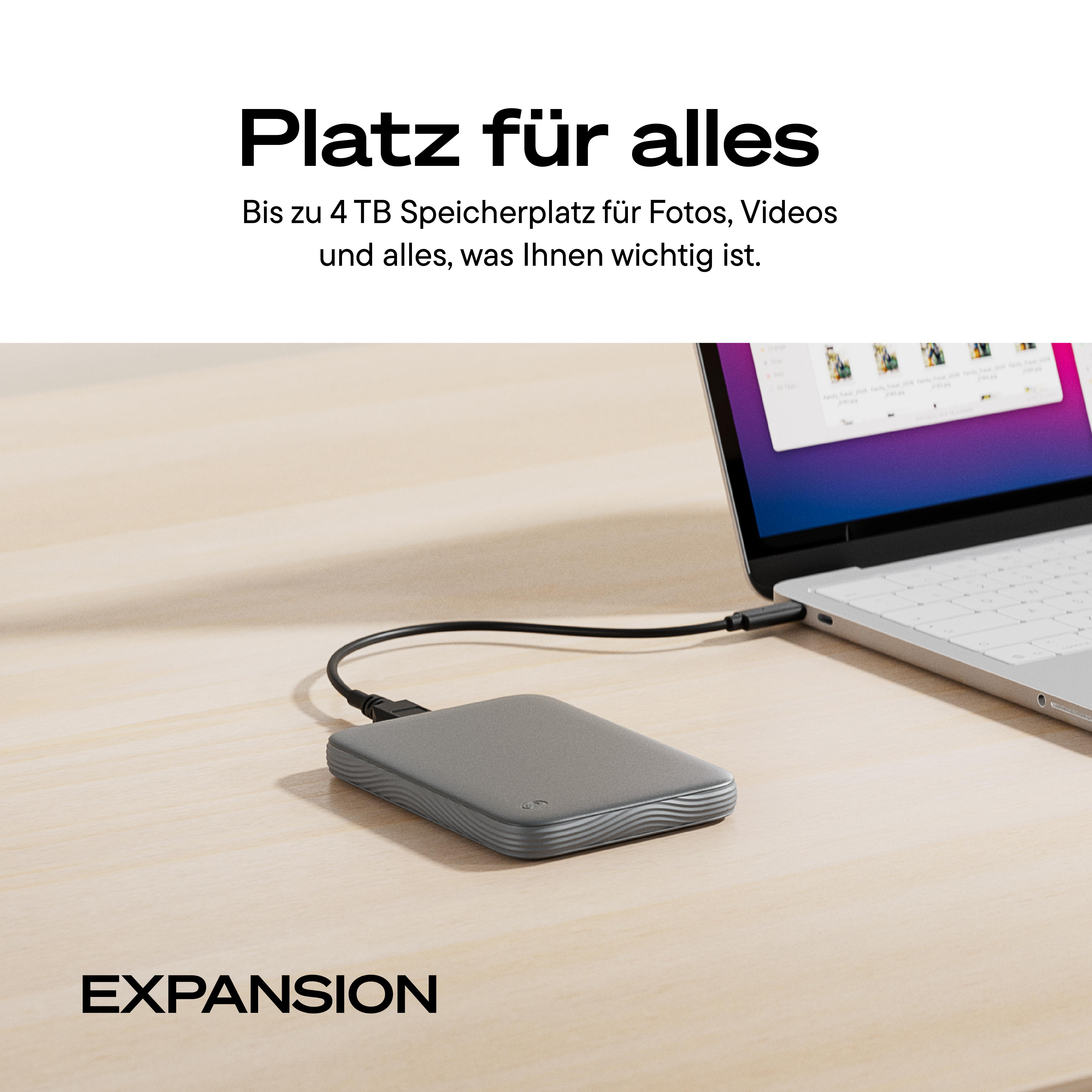 Eine graue externe Festplatte verbunden mit einem Laptop auf einem Holztisch, mit Text oben und unten.