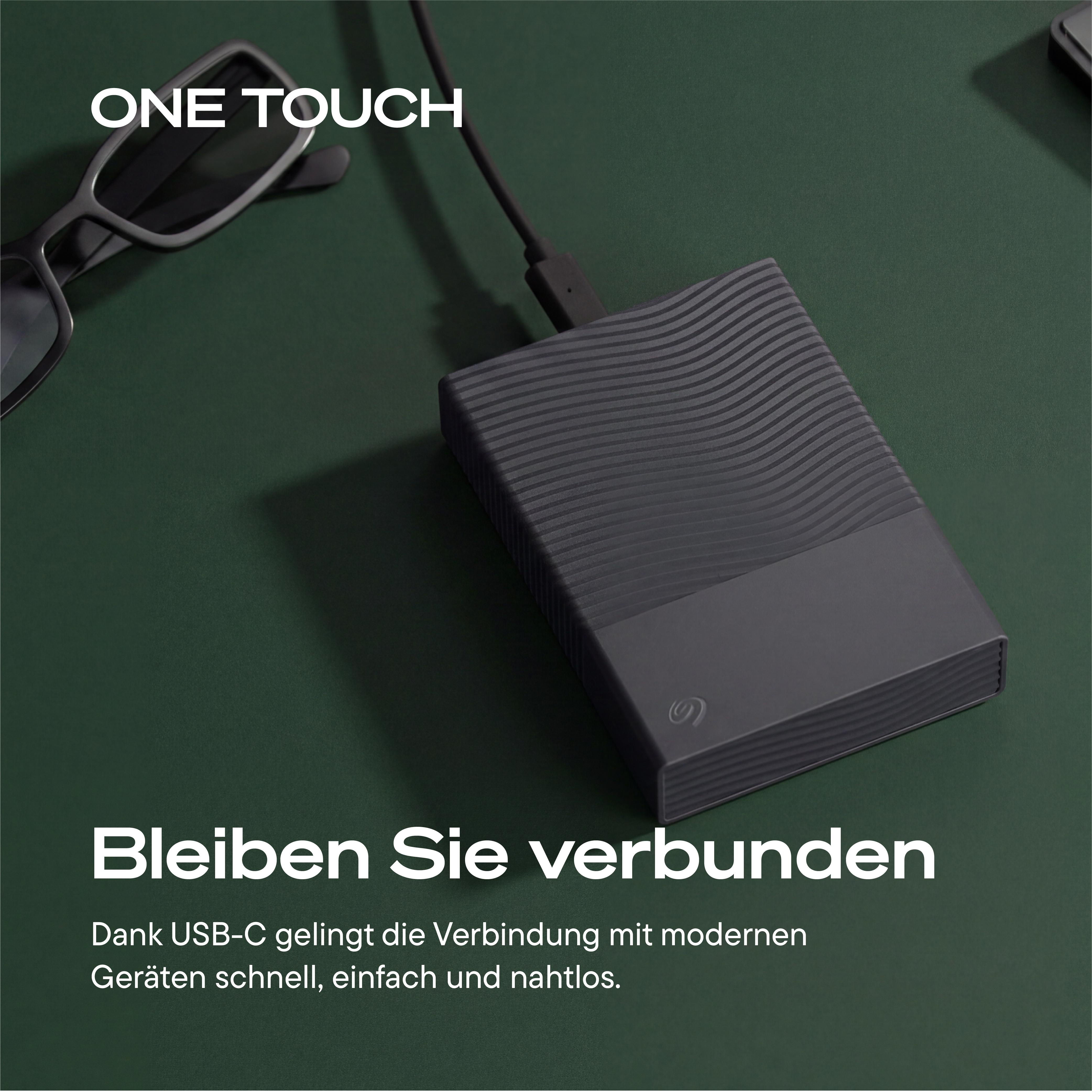 Eine schwarze Seagate One Touch Festplatte mit USB-C Kabel auf grünem Hintergrund, daneben eine Brille.