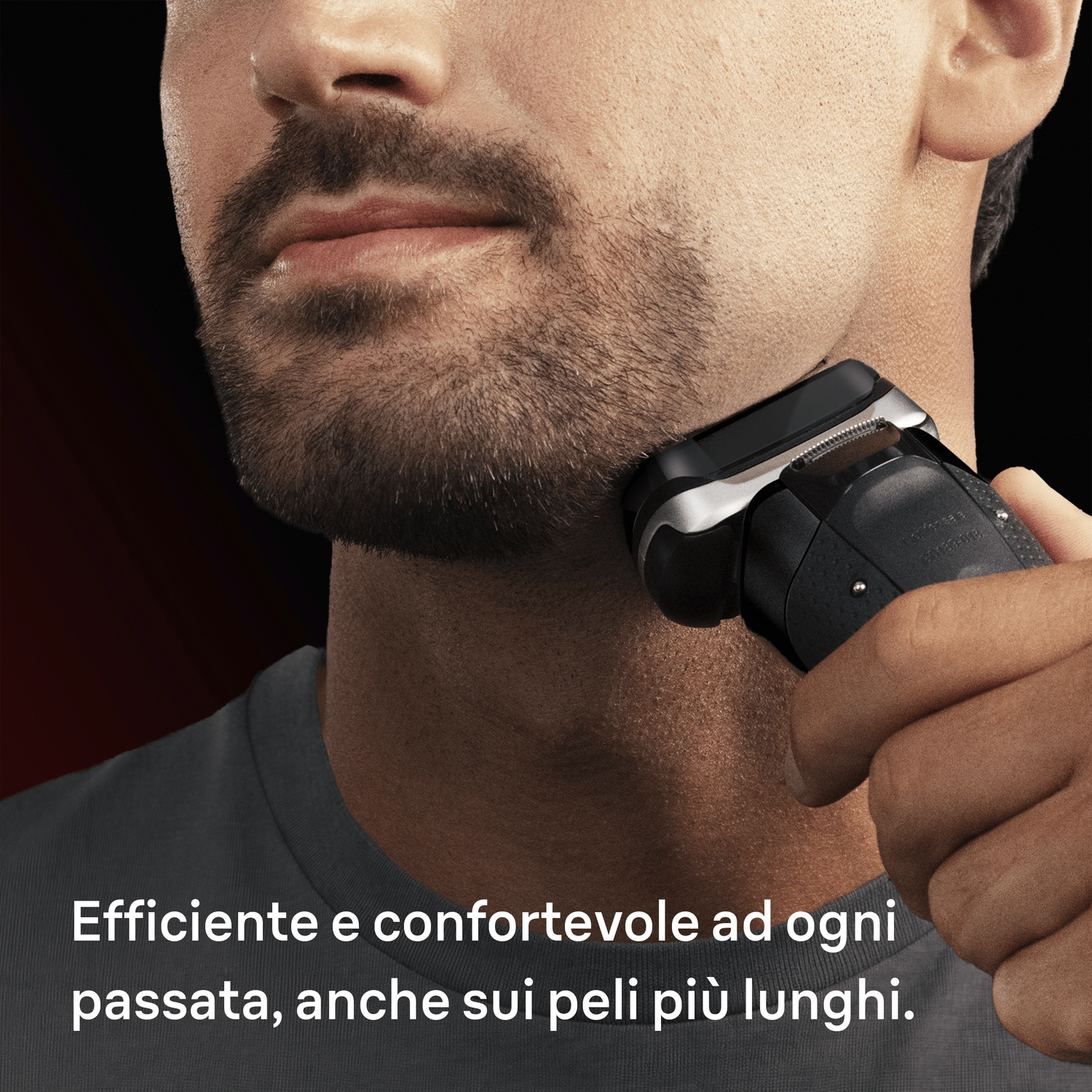 Un uomo si rade il collo con un rasoio elettrico nero su sfondo scuro.
