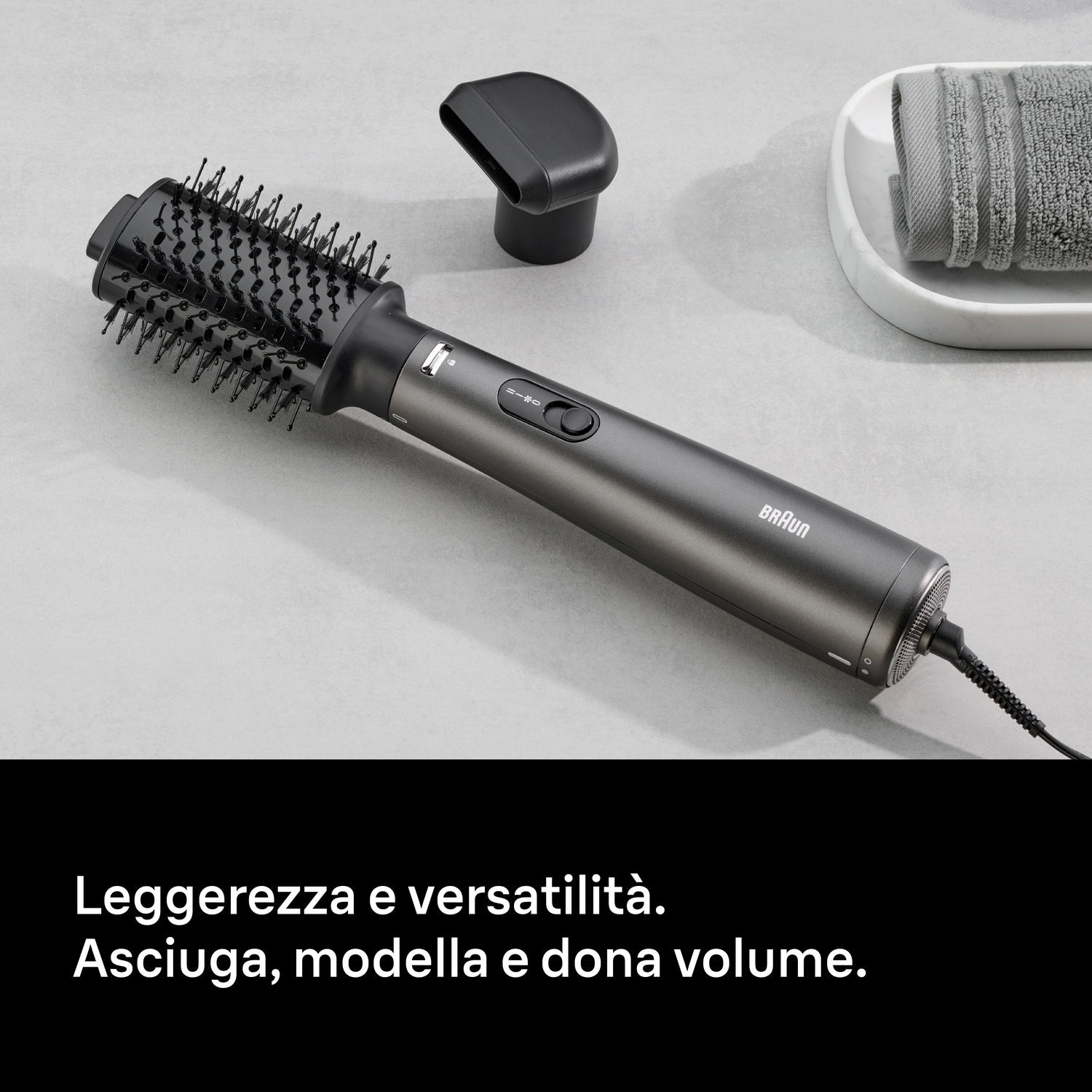 Una spazzola ad aria Braun grigio scuro con spazzola tonda su superficie chiara.
