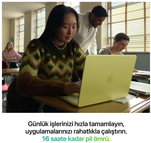 Bir kız öğrenci sınıfta açık yeşil bir dizüstü bilgisayarda çalışıyor.