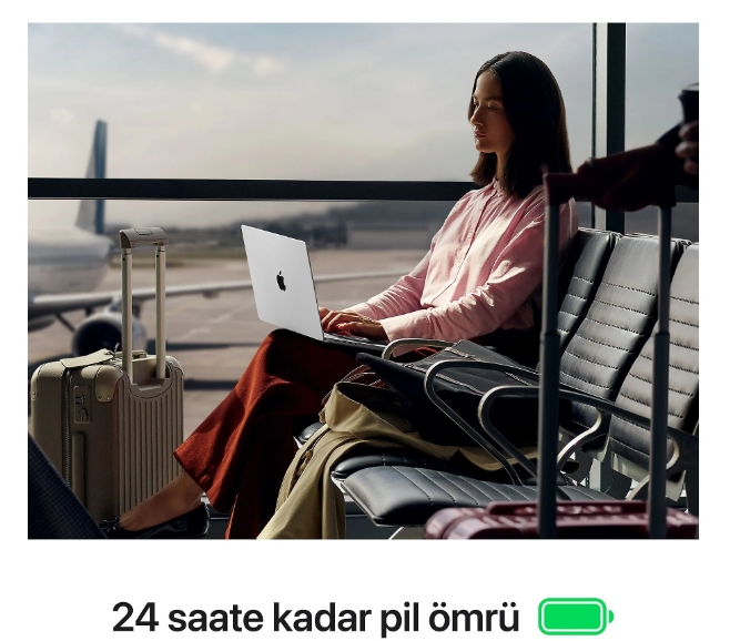 Bir kadın havalimanı bekleme alanında oturuyor, dışarıda bir uçak varken dizüstü bilgisayar kullanıyor.