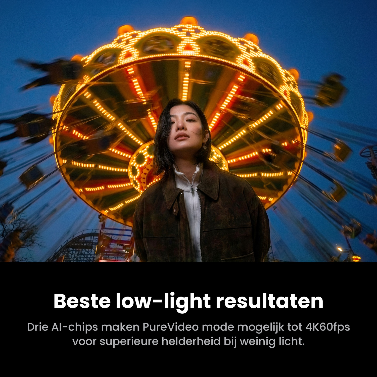 A woman in a jacket stands before a brightly lit, spinning amusement ride at night.