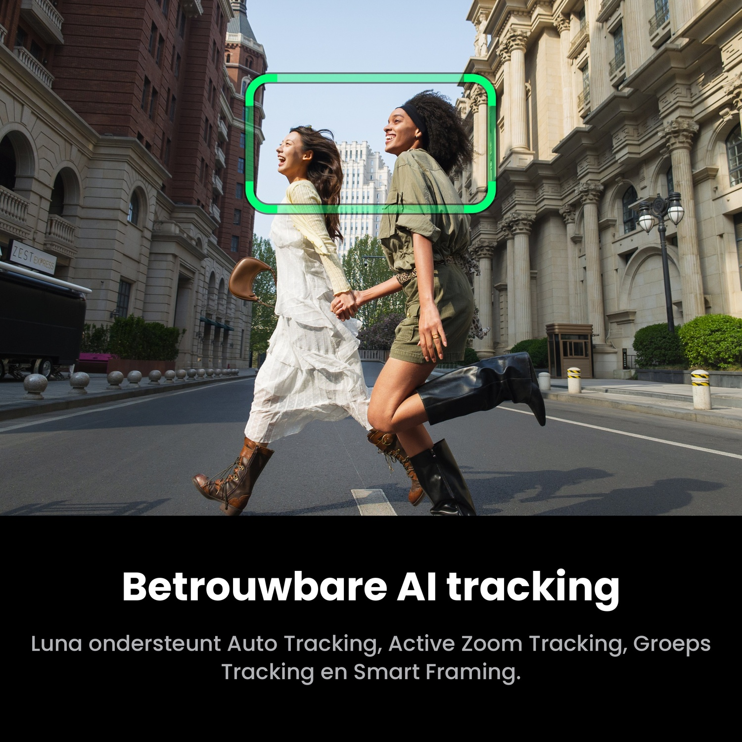 Two smiling women walk happily down a city street lined with tall historic buildings under a green tracking frame.