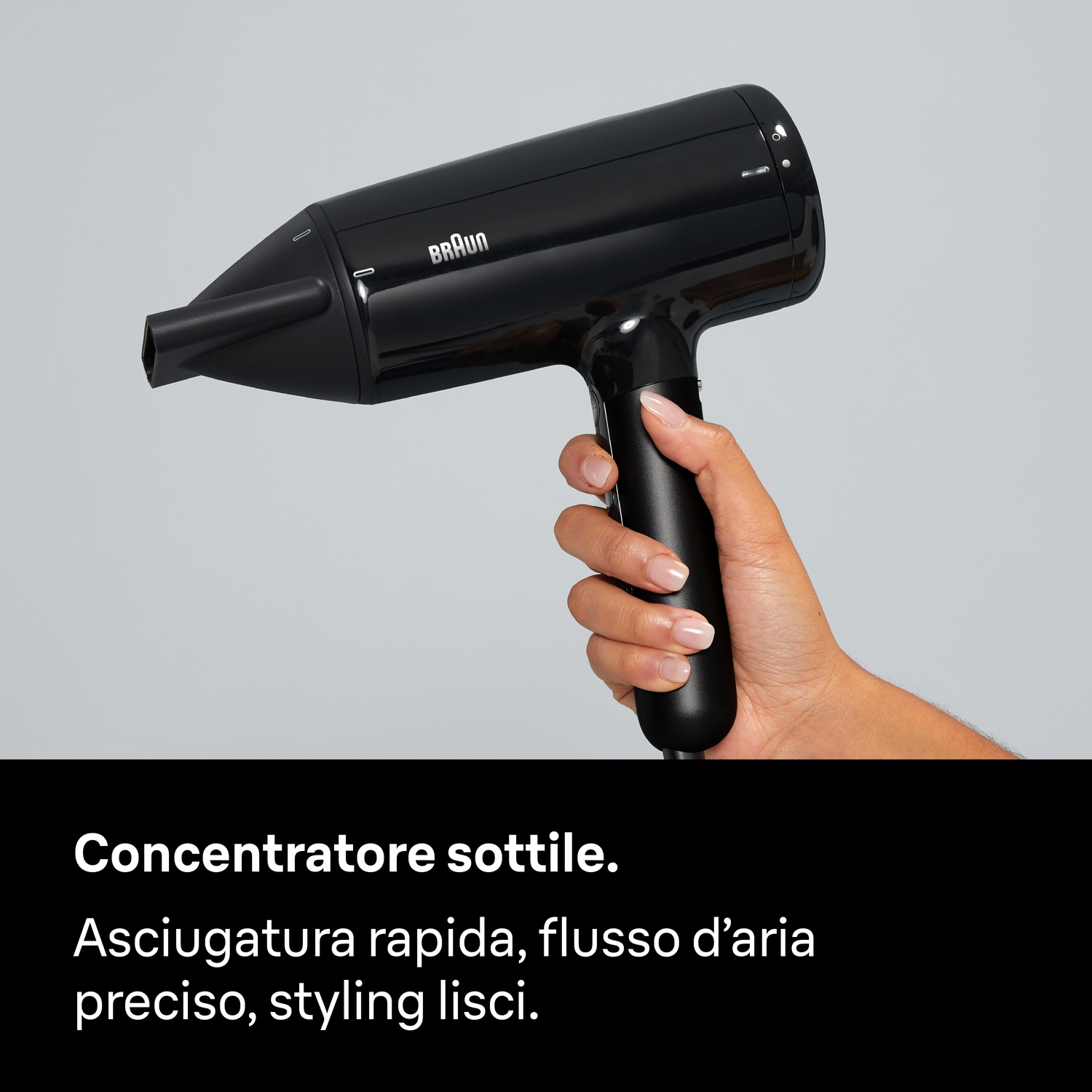 Una mano regge un asciugacapelli Braun nero su sfondo grigio con testo nero in basso.