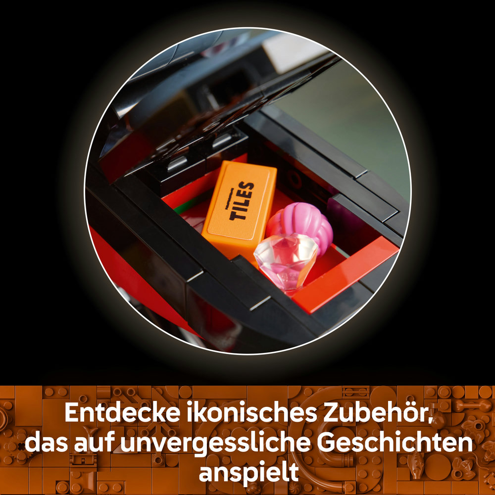 Ein offenes schwarzes Lego-Fach zeigt einen orangen Fliesenstein, einen rosafarbenen Edelstein und eine Muschel.