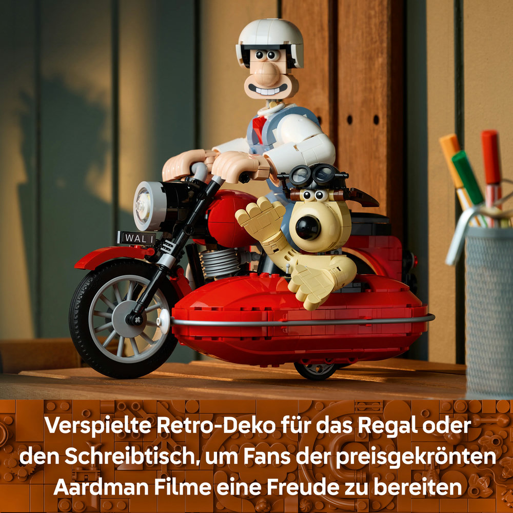 Lego Wallace und Gromit auf einem roten Motorrad mit Beiwagen auf einem Holztisch.