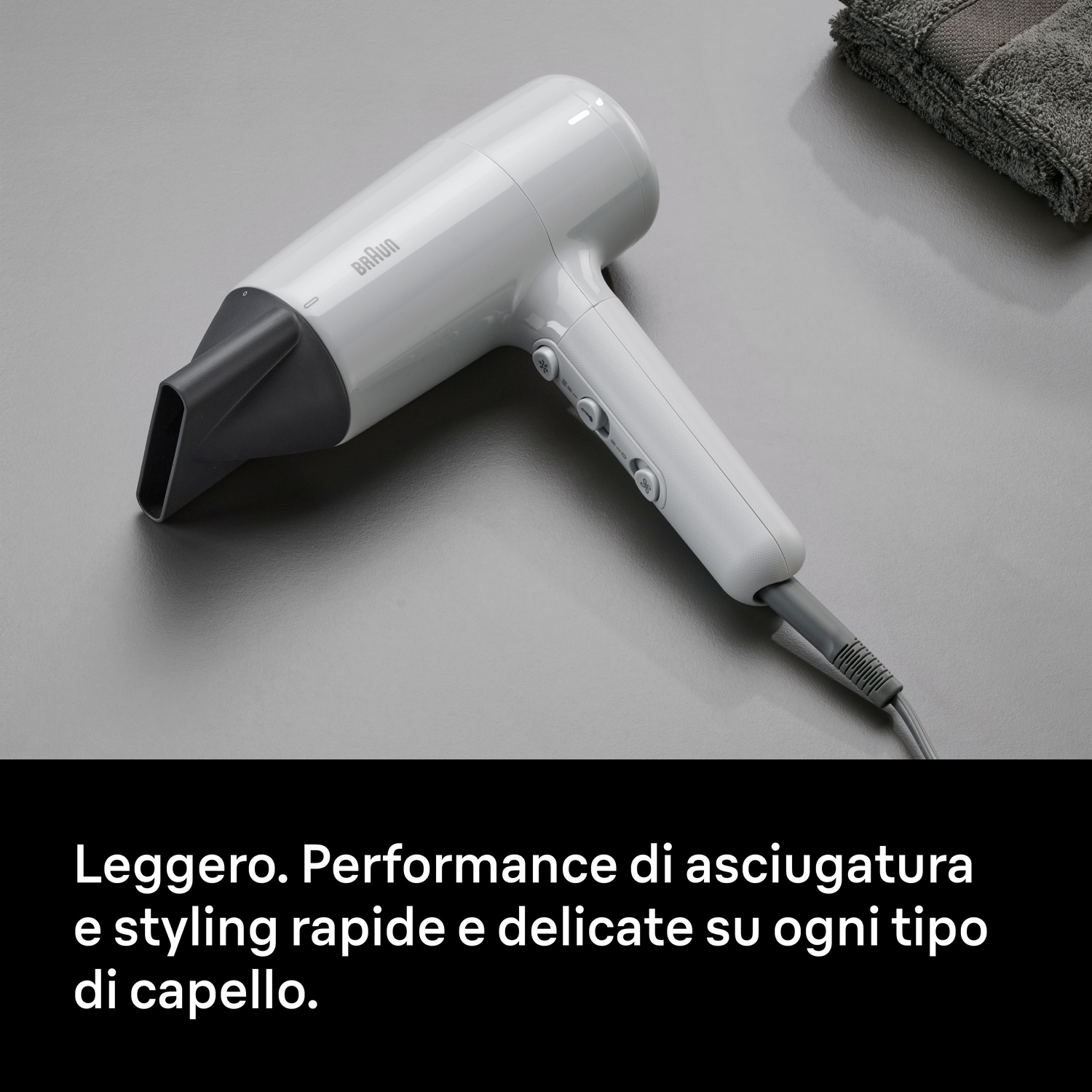 Asciugacapelli Braun grigio chiaro con beccuccio grigio scuro su superficie grigia, asciugamano.