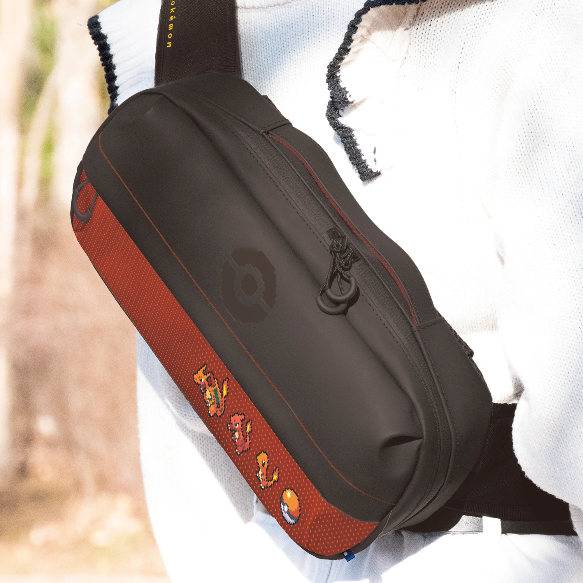 Una borsa a tracolla nera e rossa con pixel art dei Pokémon, indossata da una persona in bianco.