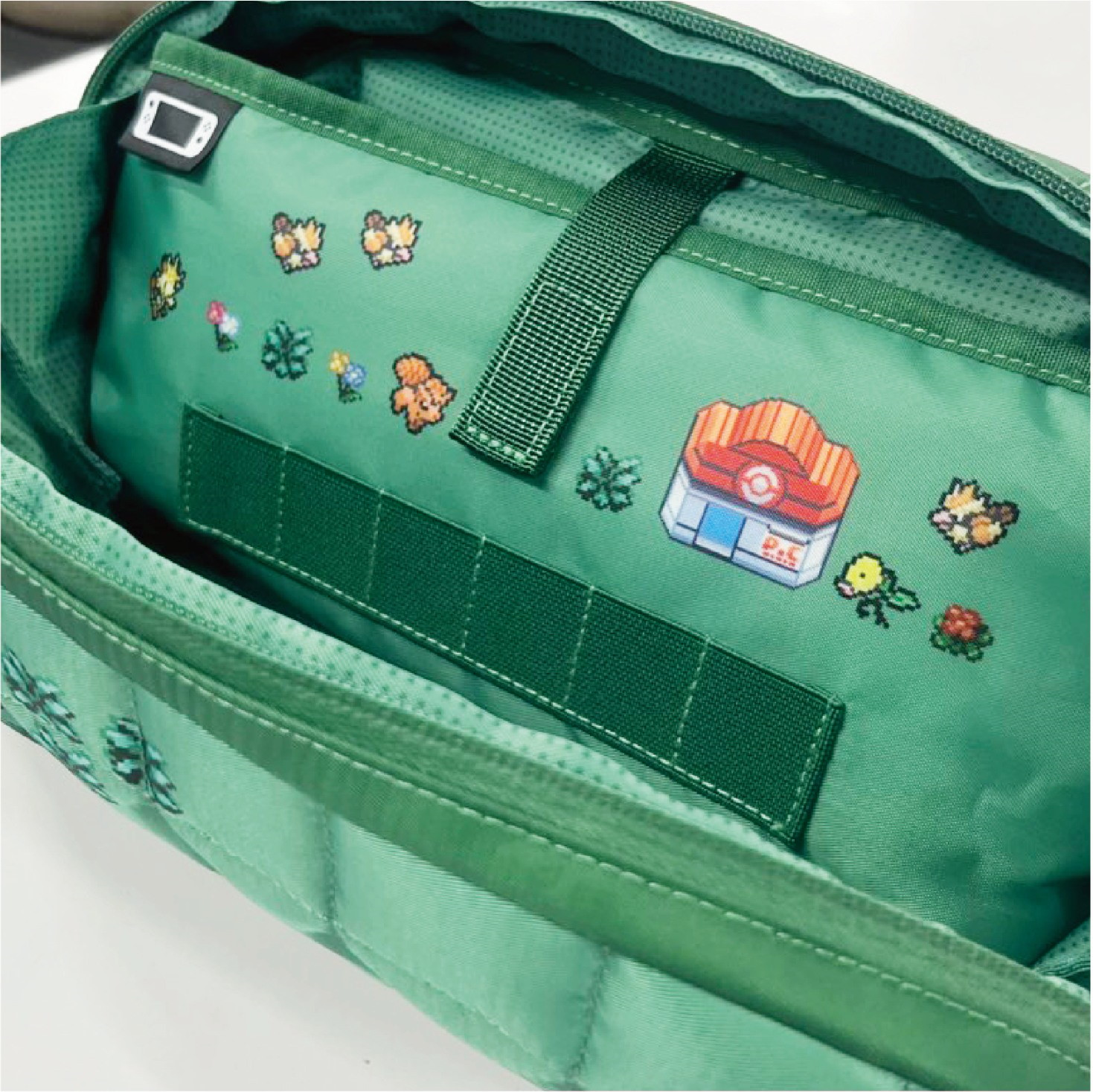 Borsa verde aperta con motivi Pokémon pixelati all'interno.