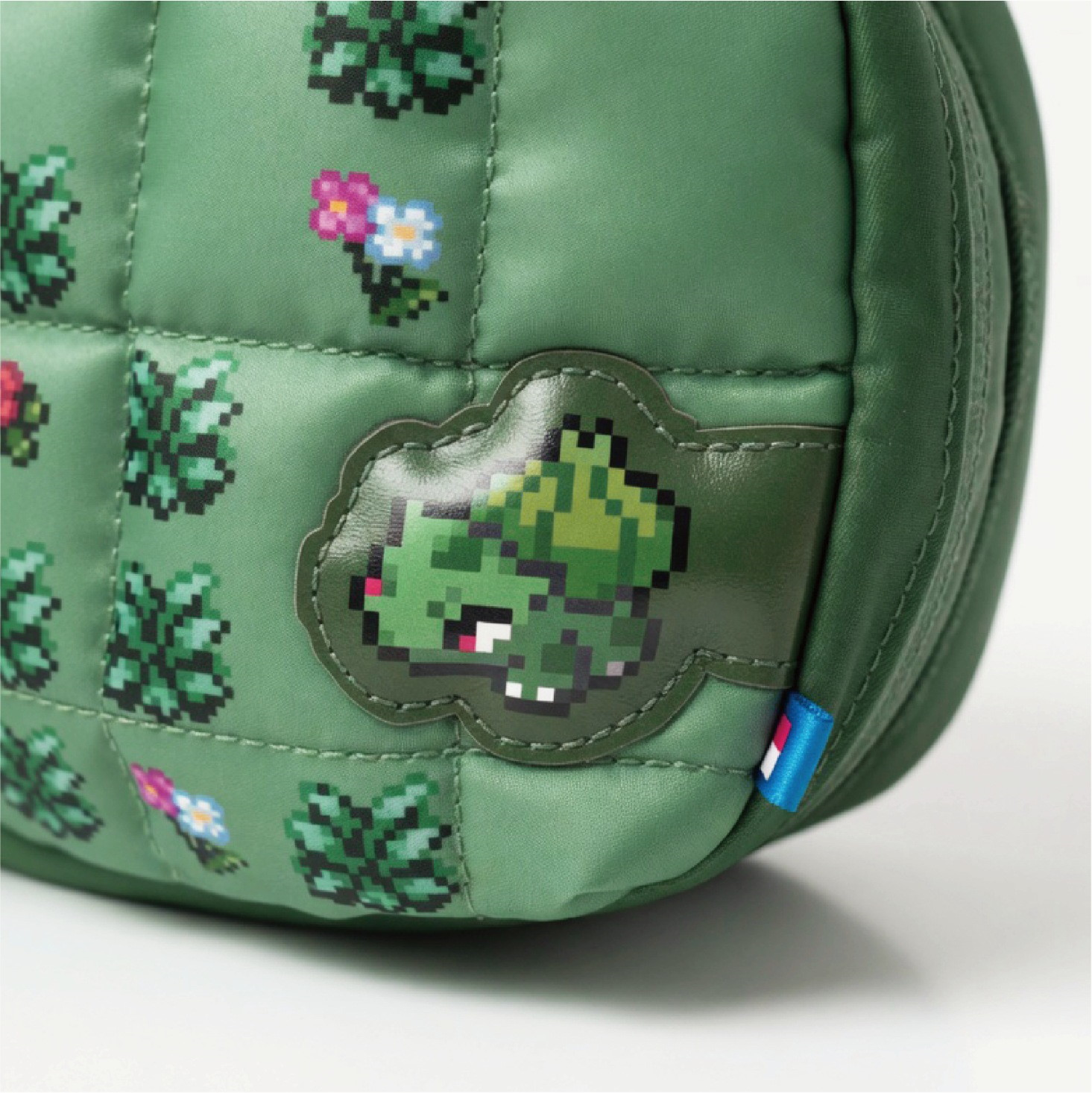 Borsa verde trapuntata con motivi di piante in pixel art e una patch di Bulbasaur.