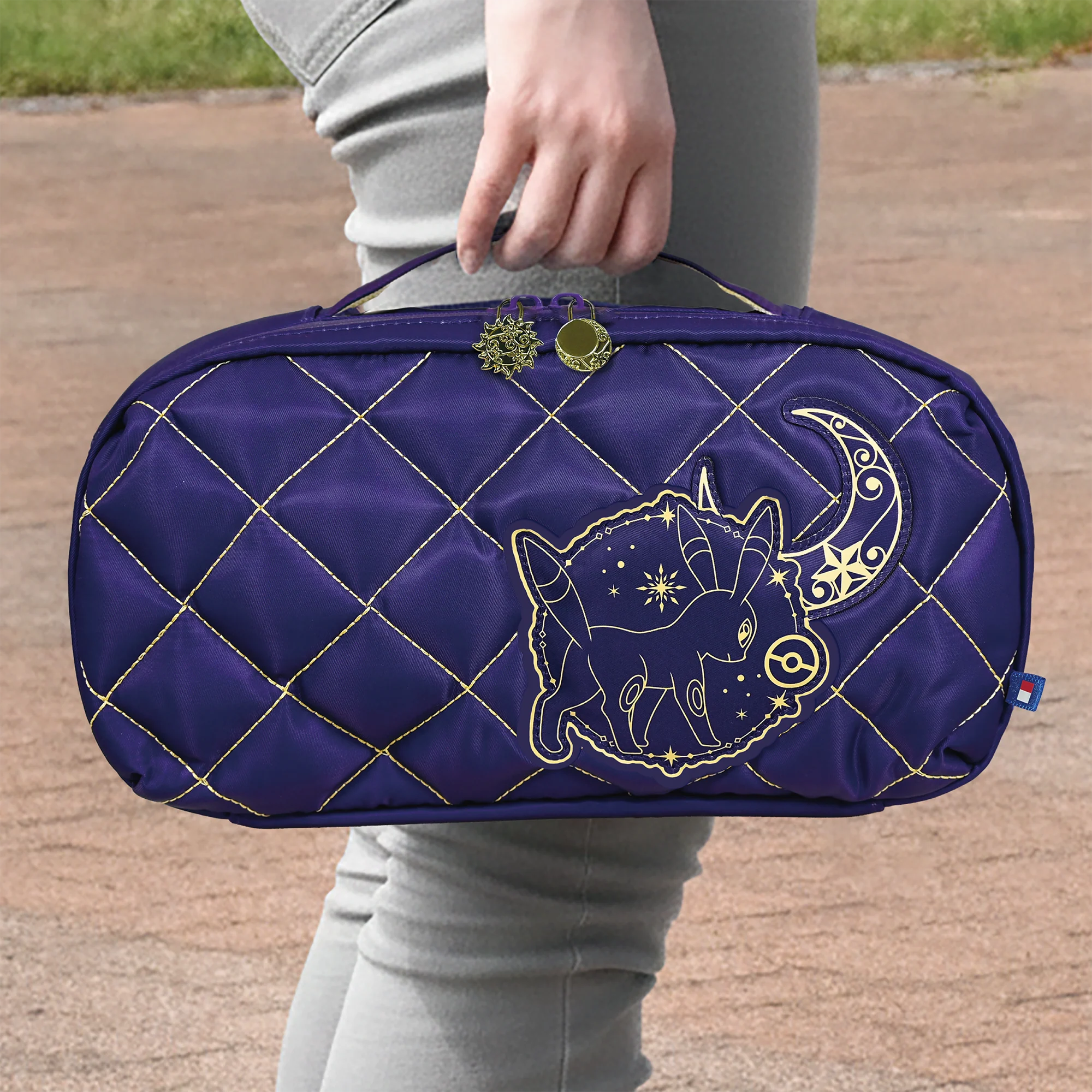 Persona che tiene una borsa viola trapuntata con un disegno dorato di luna e stelle.