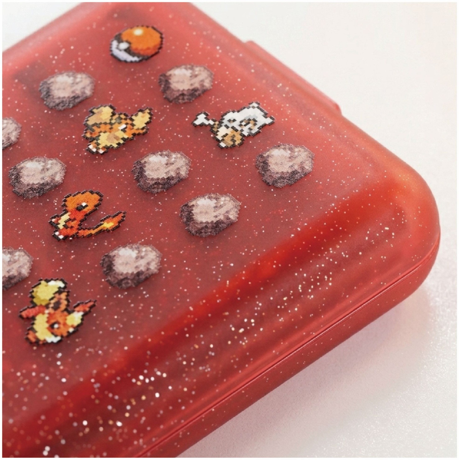 Glitzerndes rotes Gehäuse mit Pixel-Pokémon-Aufklebern und Steinen.