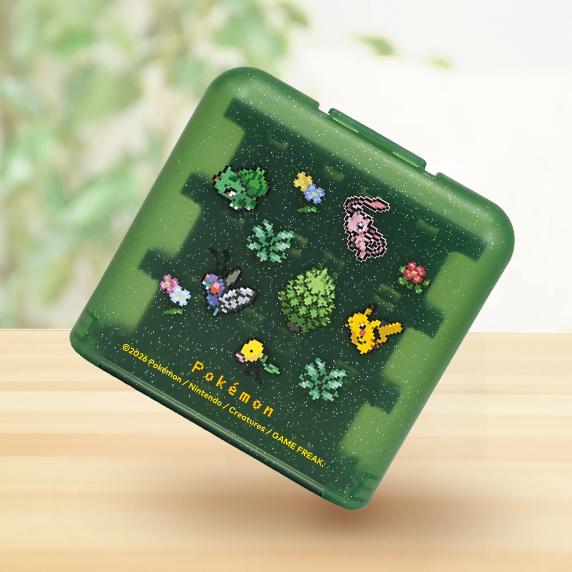 Scatola di immagazzinaggio Pokémon verde trasparente con disegni in pixel art su una superficie di legno.