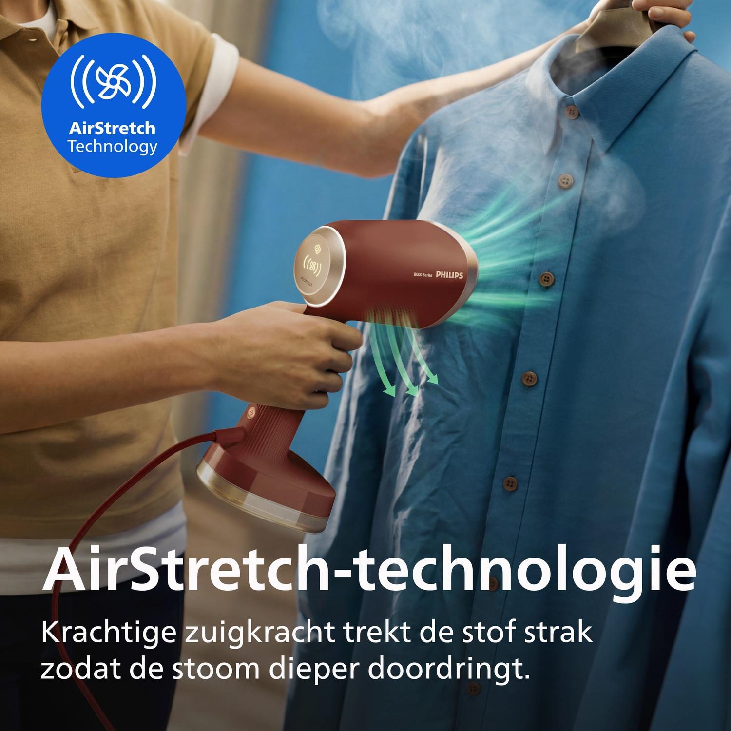 A person uses a red Philips handheld garment steamer with AirStretch technology on a blue shirt.