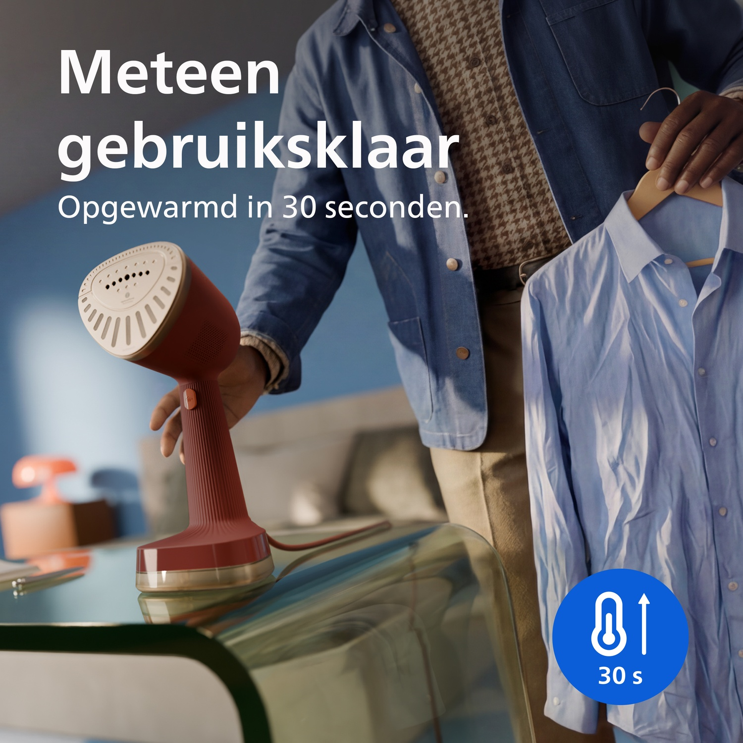 A red handheld garment steamer on a table while someone holds up a blue shirt. Text reads ready in 30 seconds.