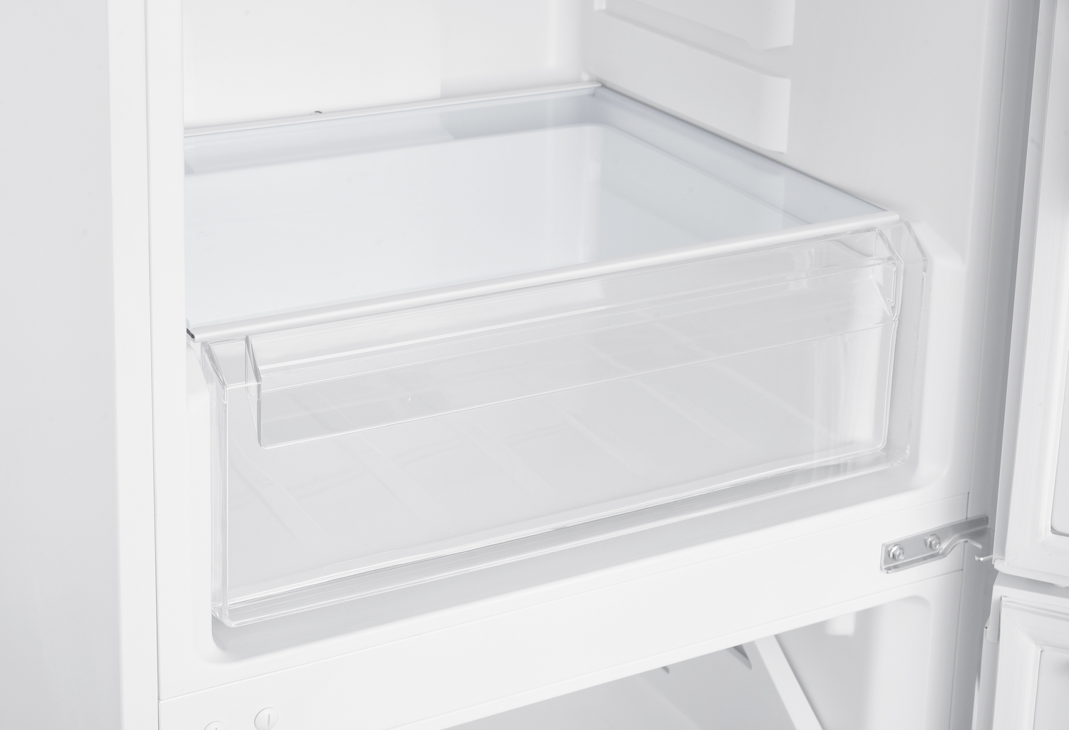 Un cajón de plástico transparente vacío dentro del interior de un refrigerador blanco limpio.