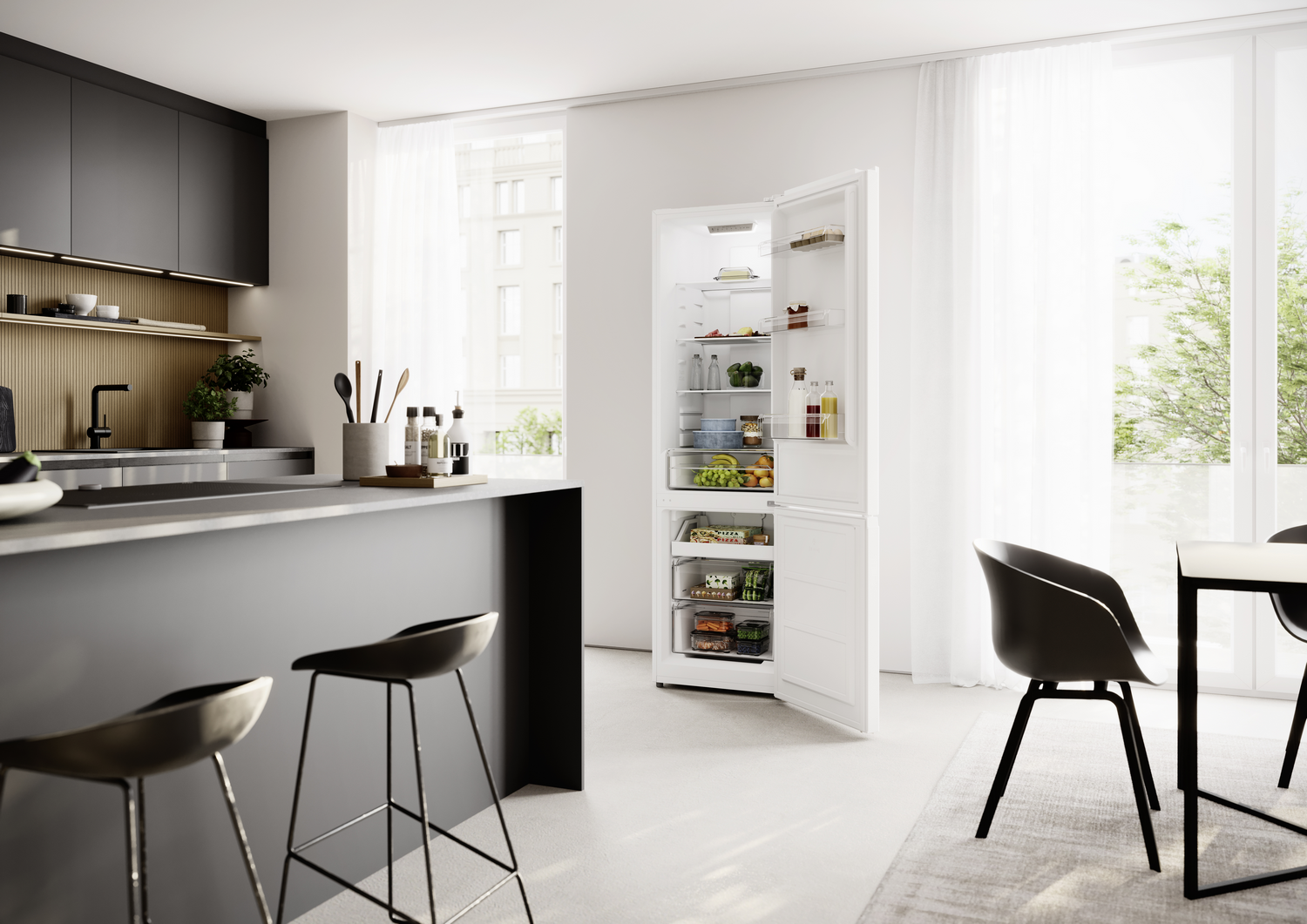 Cocina moderna con isla negra, refrigerador blanco abierto y comedor con luz natural.