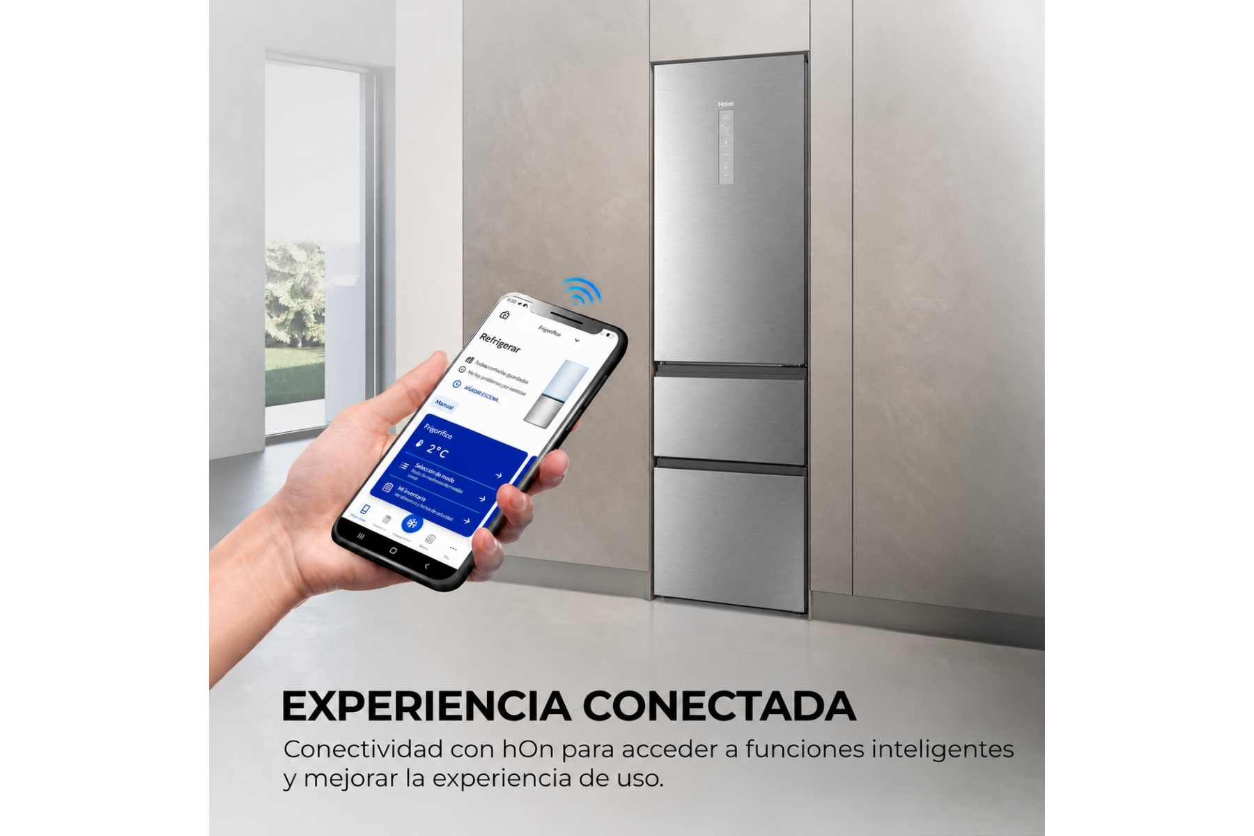 Mano sosteniendo un smartphone con una app para controlar una moderna nevera de acero inoxidable.