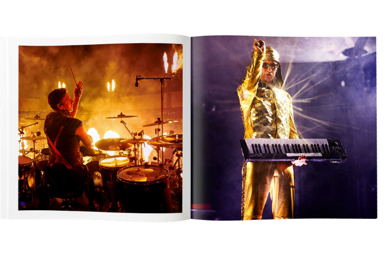 Ein offenes Fotobuch zeigt einen Schlagzeuger vor Flammen und einen Keyboarder in goldenem Glitzerkostüm auf der Bühne.