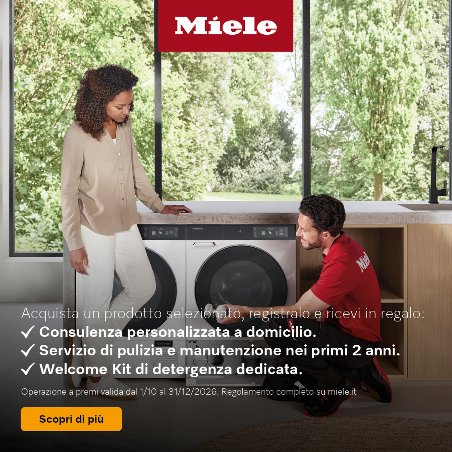 Una donna accanto a un tecnico che installa una lavatrice Miele in una cucina moderna.