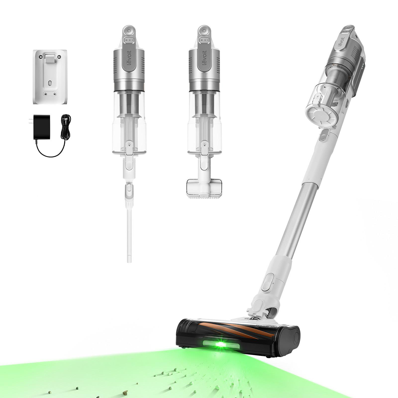 Akku-Stielsauger mit Zubehör, Ladestation und grünem Laserlicht auf dem Boden zur Stauberkennung.