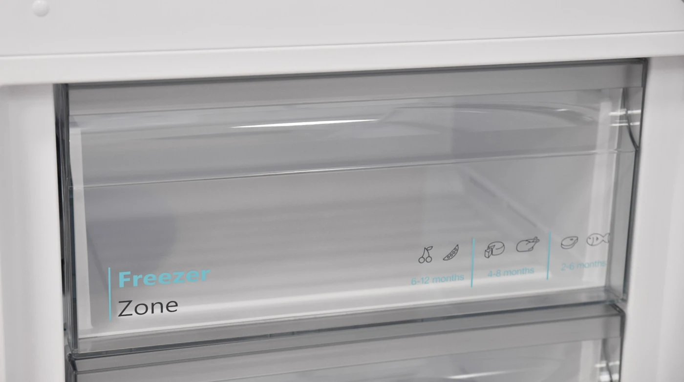 Egy fehér fagyasztó átlátszó fiókkal, rajta a "Freezer Zone" felirattal és élelmiszerikonokkal.