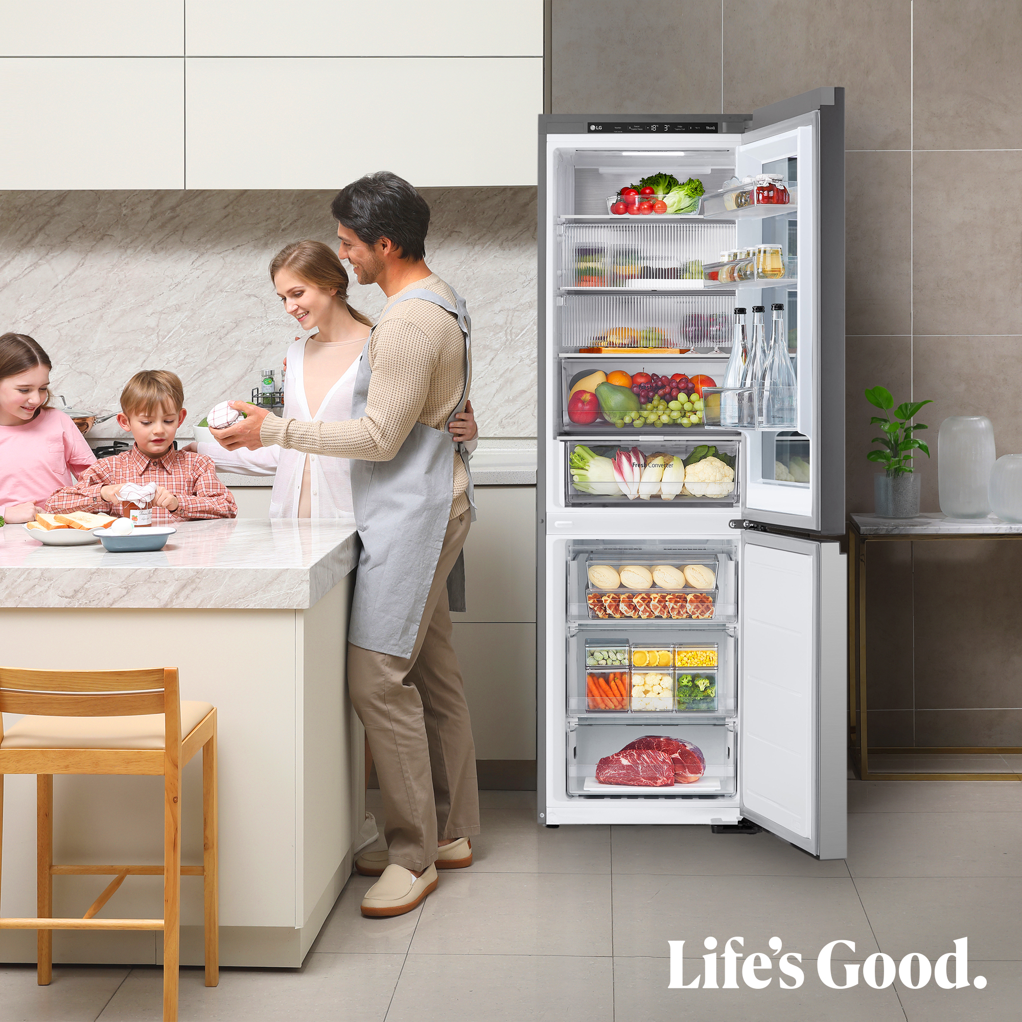 Una familia en la cocina junto a un refrigerador LG abierto lleno de comida.