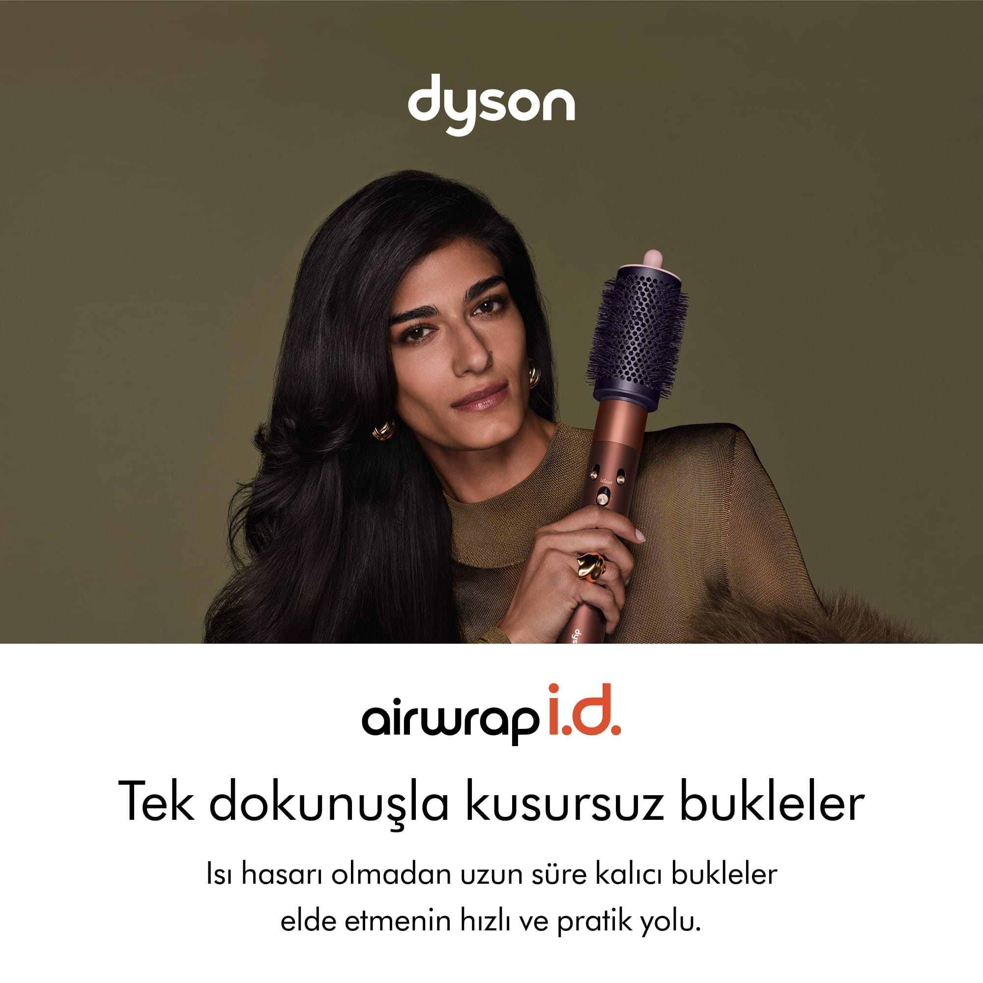 Zeytin yeşili arka plan önünde Dyson Airwrap i.d. saç şekillendiriciyi tutan bir kadın.