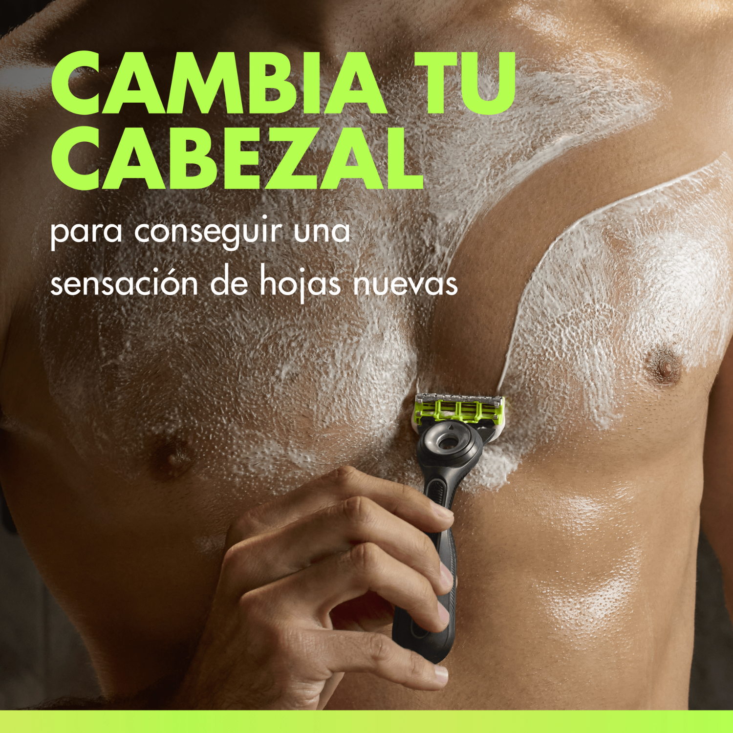 Un hombre se afeita el pecho con espuma blanca, sosteniendo una maquinilla negra y verde en la mano.