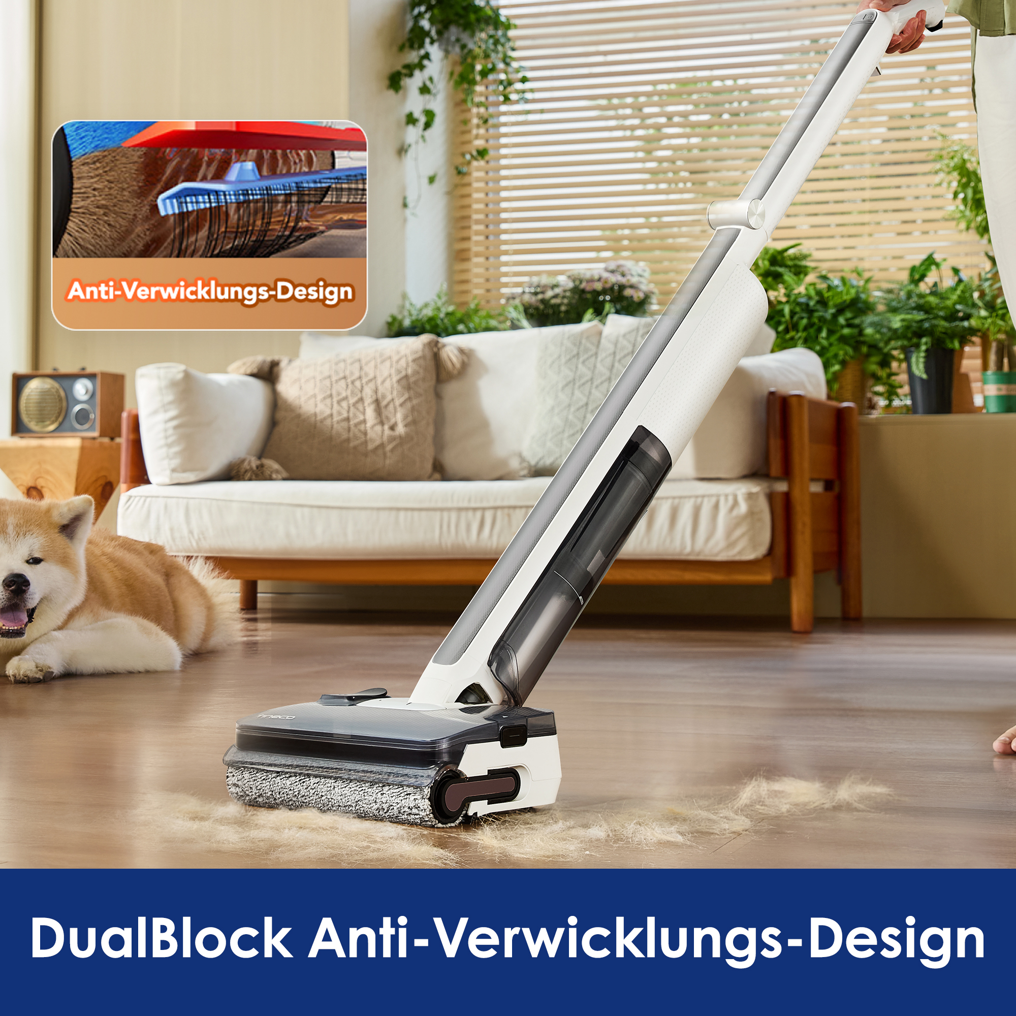Ein weißer Akku-Staubsauger entfernt Tierhaare von einem Holzboden. Eine Akita-Hündin liegt im Hintergrund auf einem Teppich.