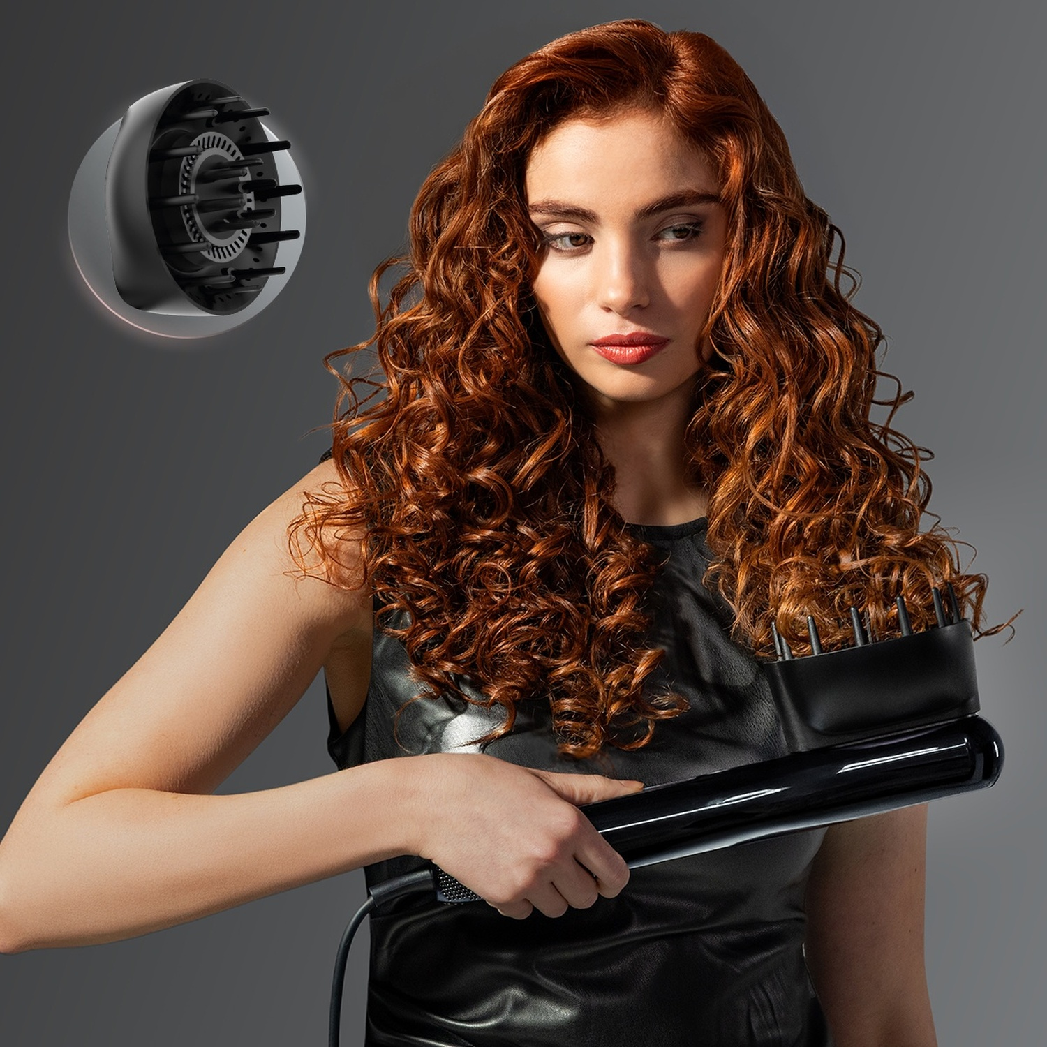 Una donna con lunghi ricci rossi tiene in mano un ferro per capelli nero, con un diffusore in alto a sinistra.