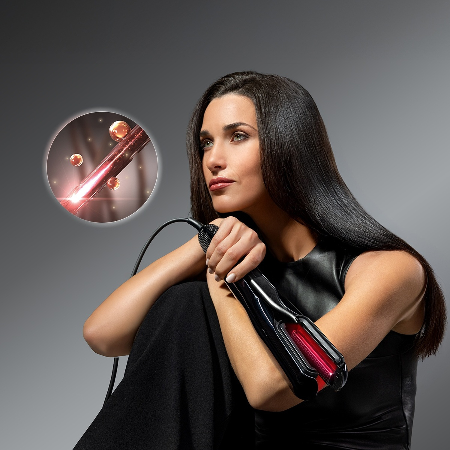 Una donna con lunghi capelli neri tiene una piastra. Un cerchio ingrandito mostra capelli lucidi con particelle.