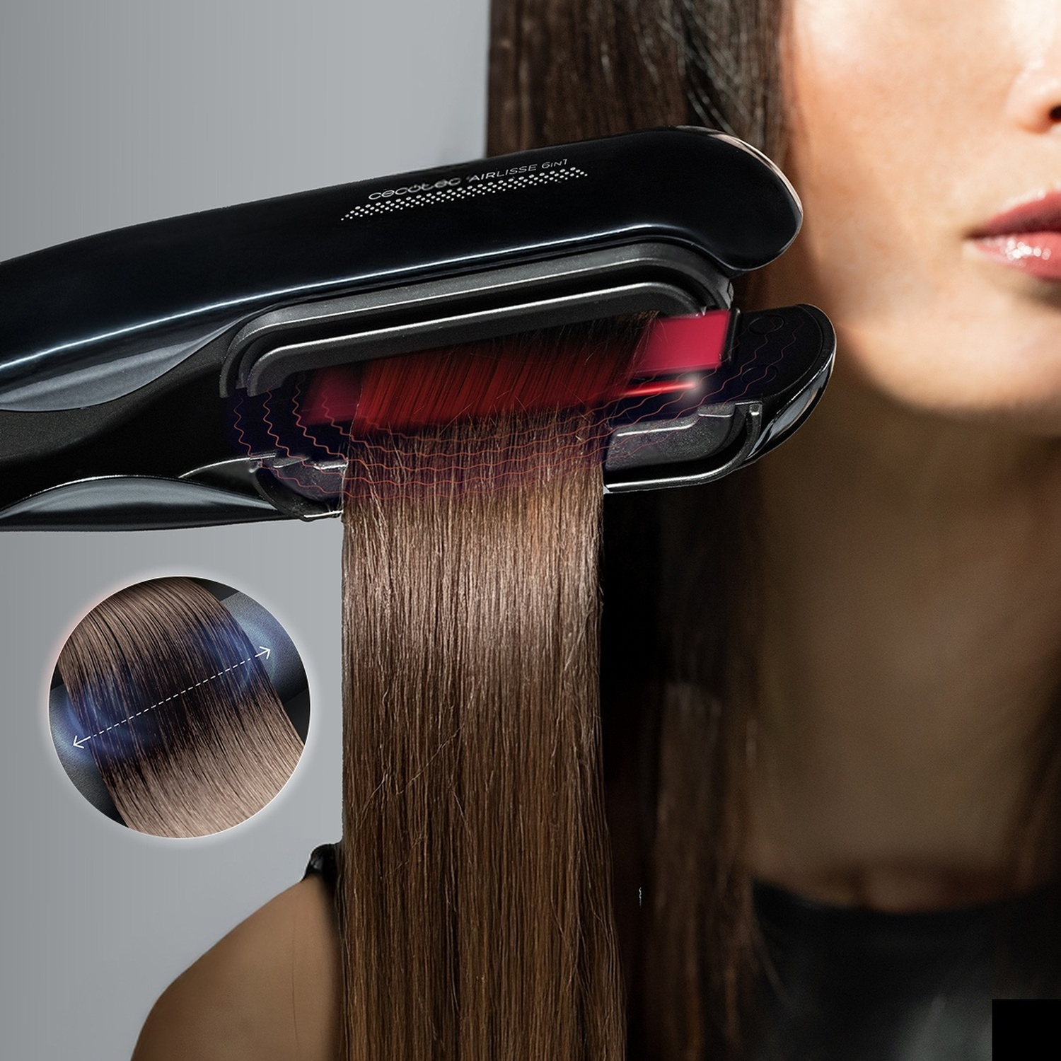 Un ferro per capelli nero liscia una ciocca di capelli castani con effetti di luce rossa.