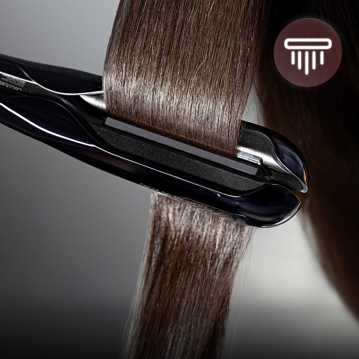 Una ciocca di capelli castani e lucidi viene lisciata con una piastra nera.