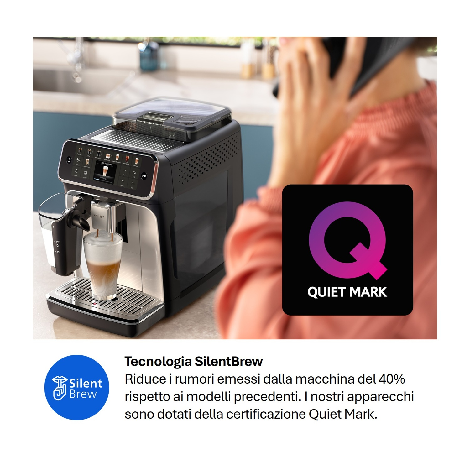 Macchina da caffè prepara un latte macchiato, una persona parla al telefono sullo sfondo, logo Quiet Mark.