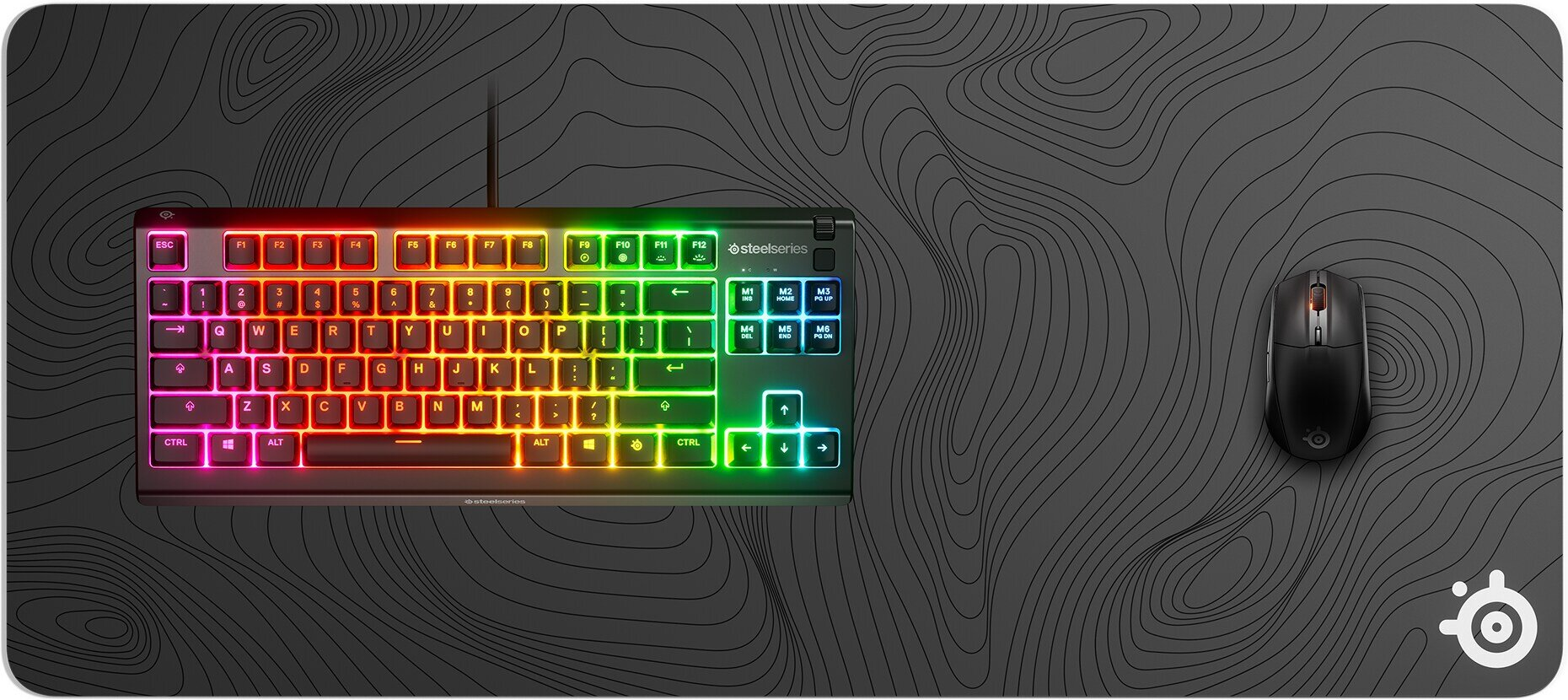 Klawiatura i mysz RGB SteelSeries spoczywają na czarnej podkładce z motywem topograficznym.