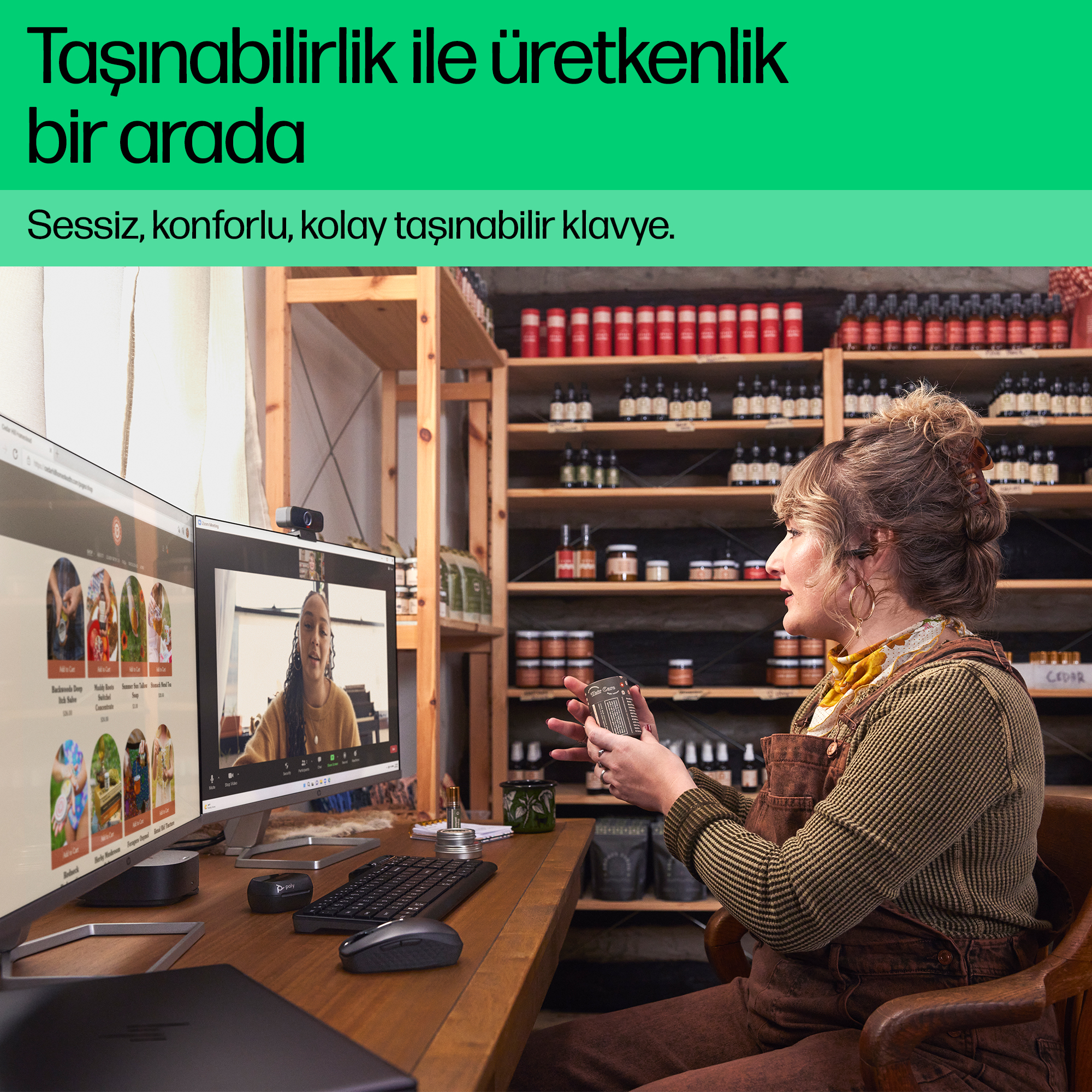 Bir kadın çift monitörlü bir masada çalışırken küçük bir ürün tutuyor.