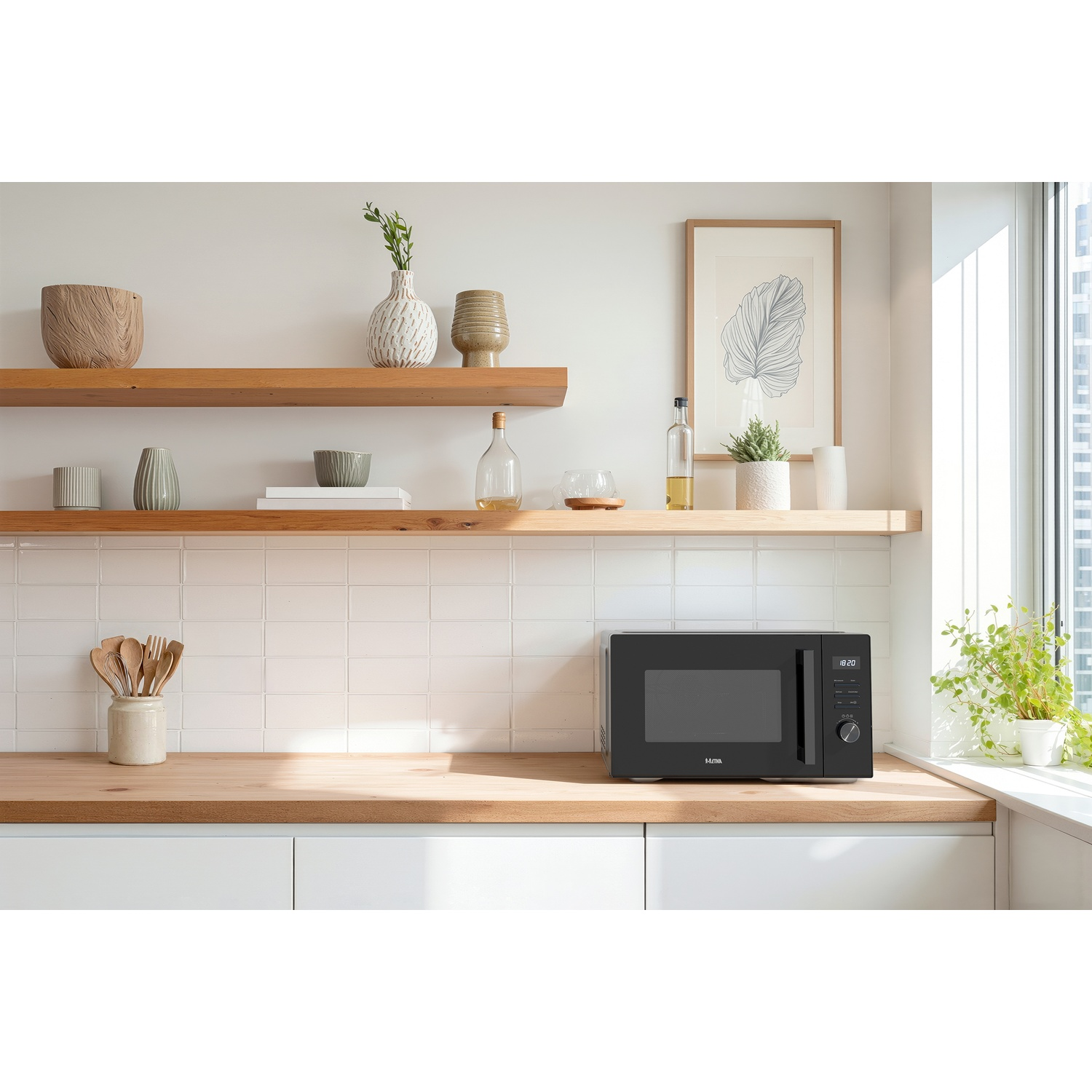 A black microwave sits on a wooden kitchen counter below shelves with vases, plants, and a framed botanical picture.
