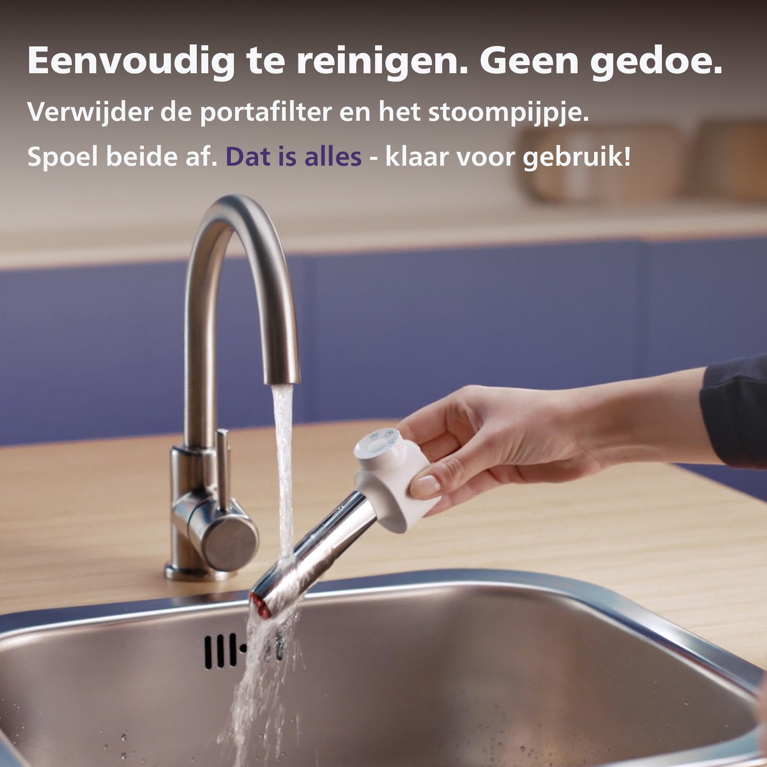 A hand washes a coffee machine nozzle under running water in a kitchen sink.