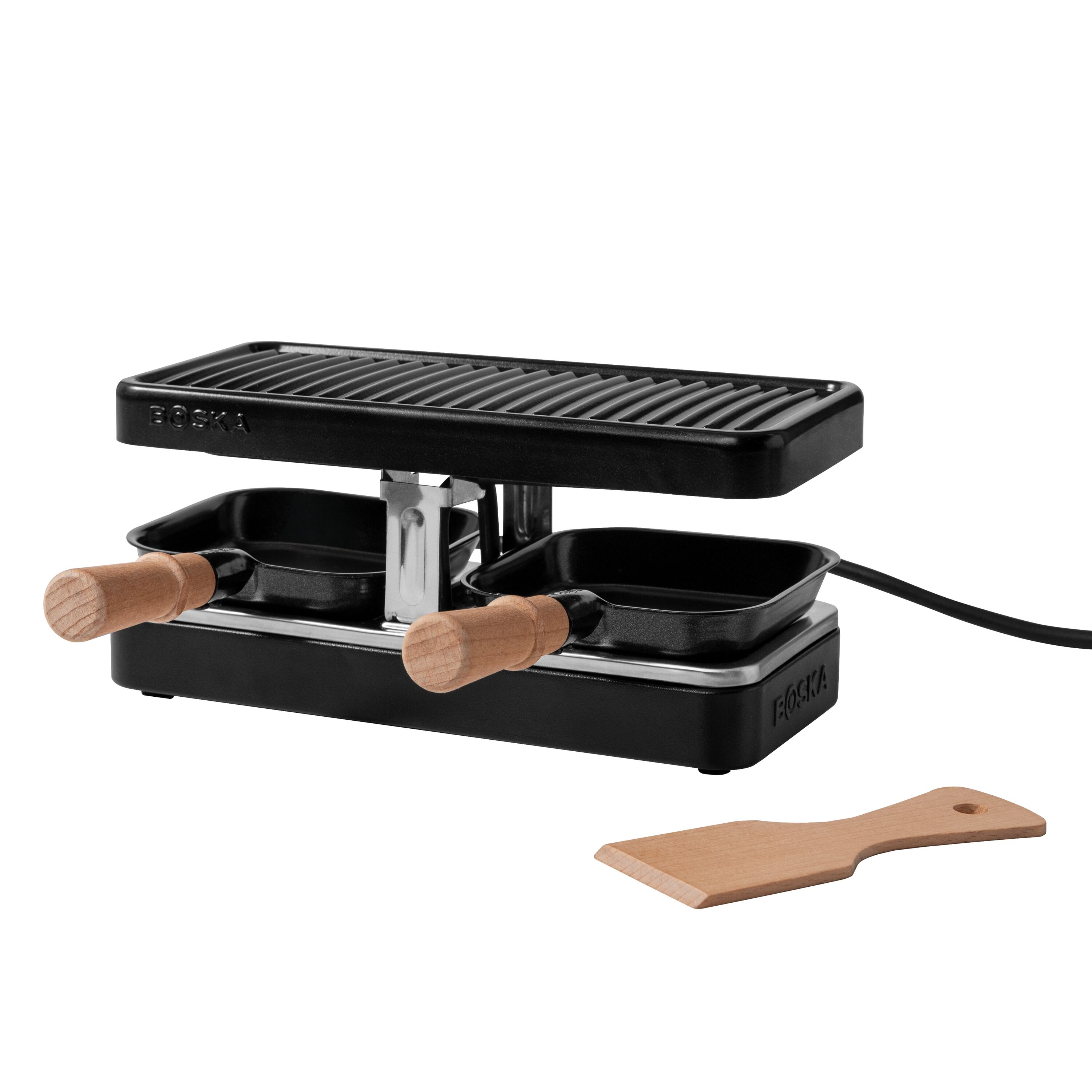 Ein schwarzer Raclette-Grill mit zwei Pfännchen mit Holzgriffen und einem Holzwender auf weißem Hintergrund.