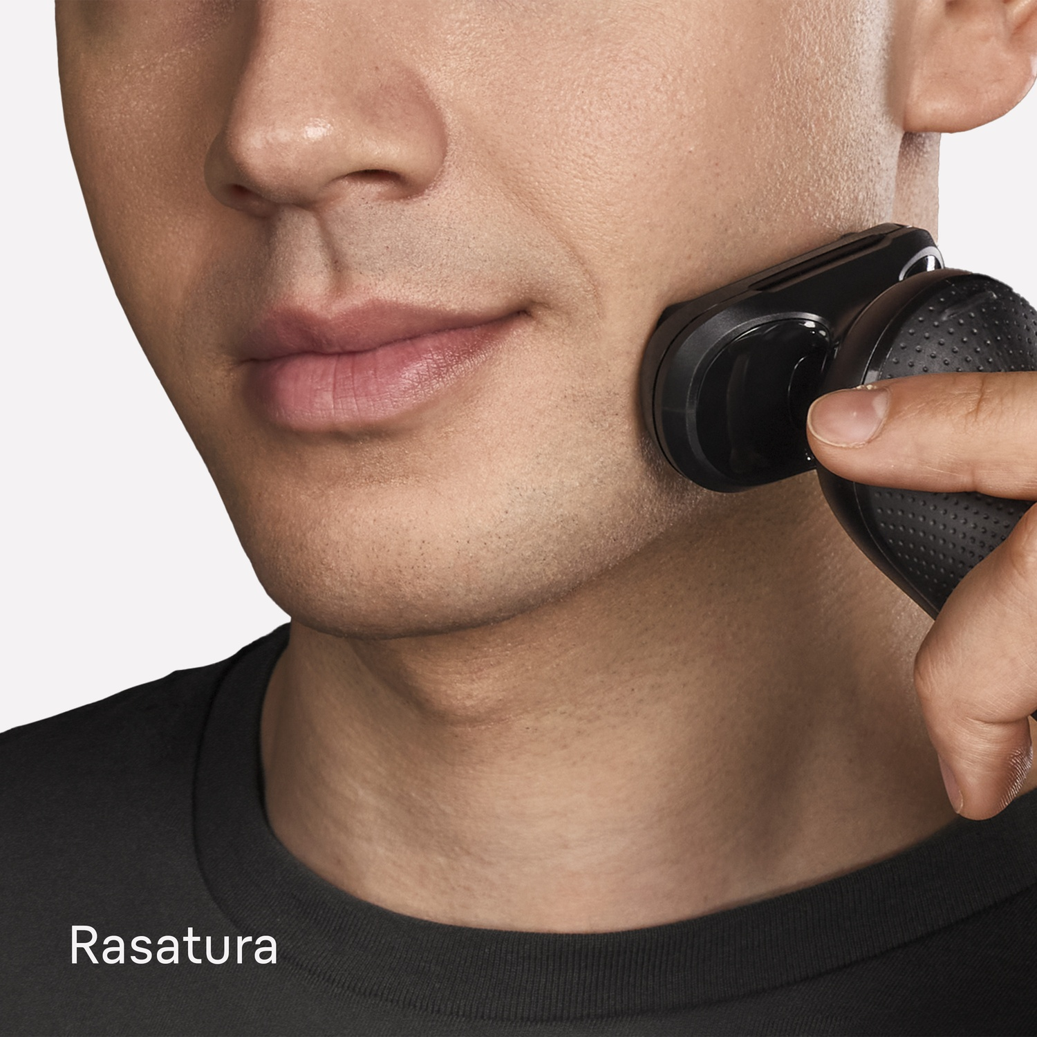 Un uomo si rade la guancia con un rasoio elettrico nero.